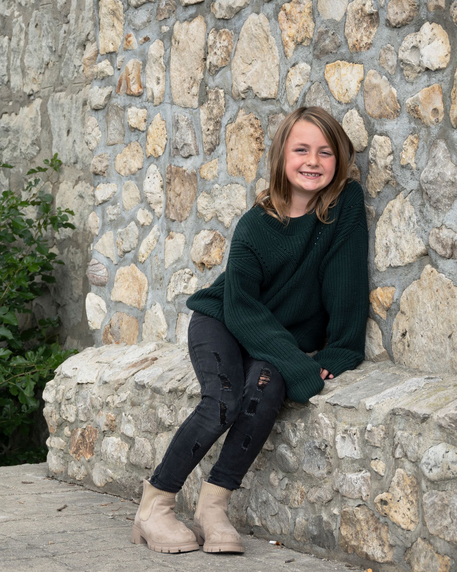 A series of casual portraits taken against a stone wall showing someone sitting and smiling.