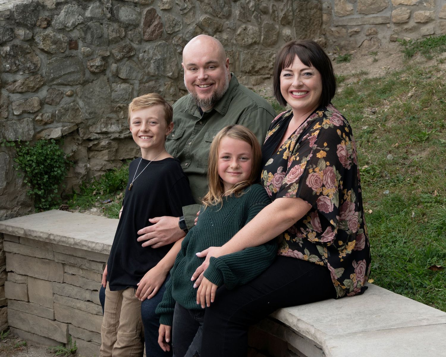 Family group photos taken against a rustic stone wall backdrop.