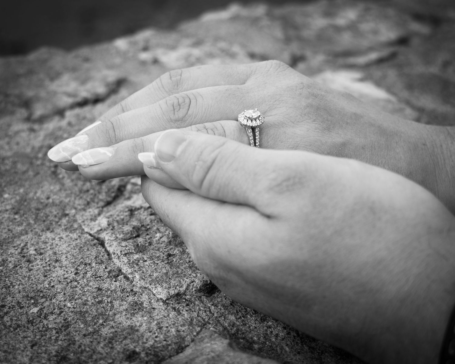 Close-up sequence of hands displaying an engagement ring on a stone surface.
