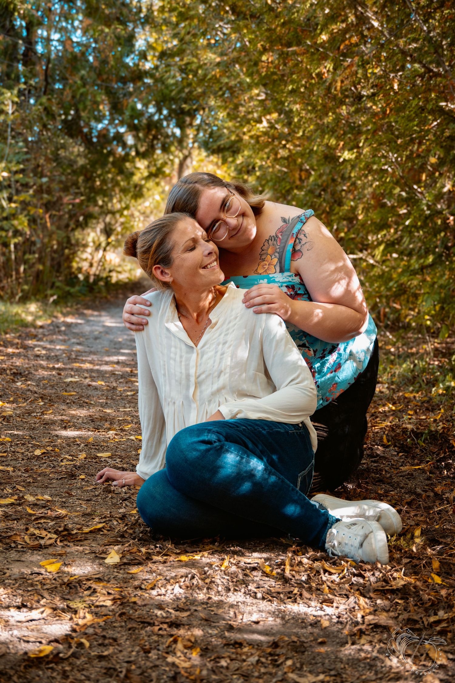 Playful autumn photoshoot with two people laying in fallen leaves.
