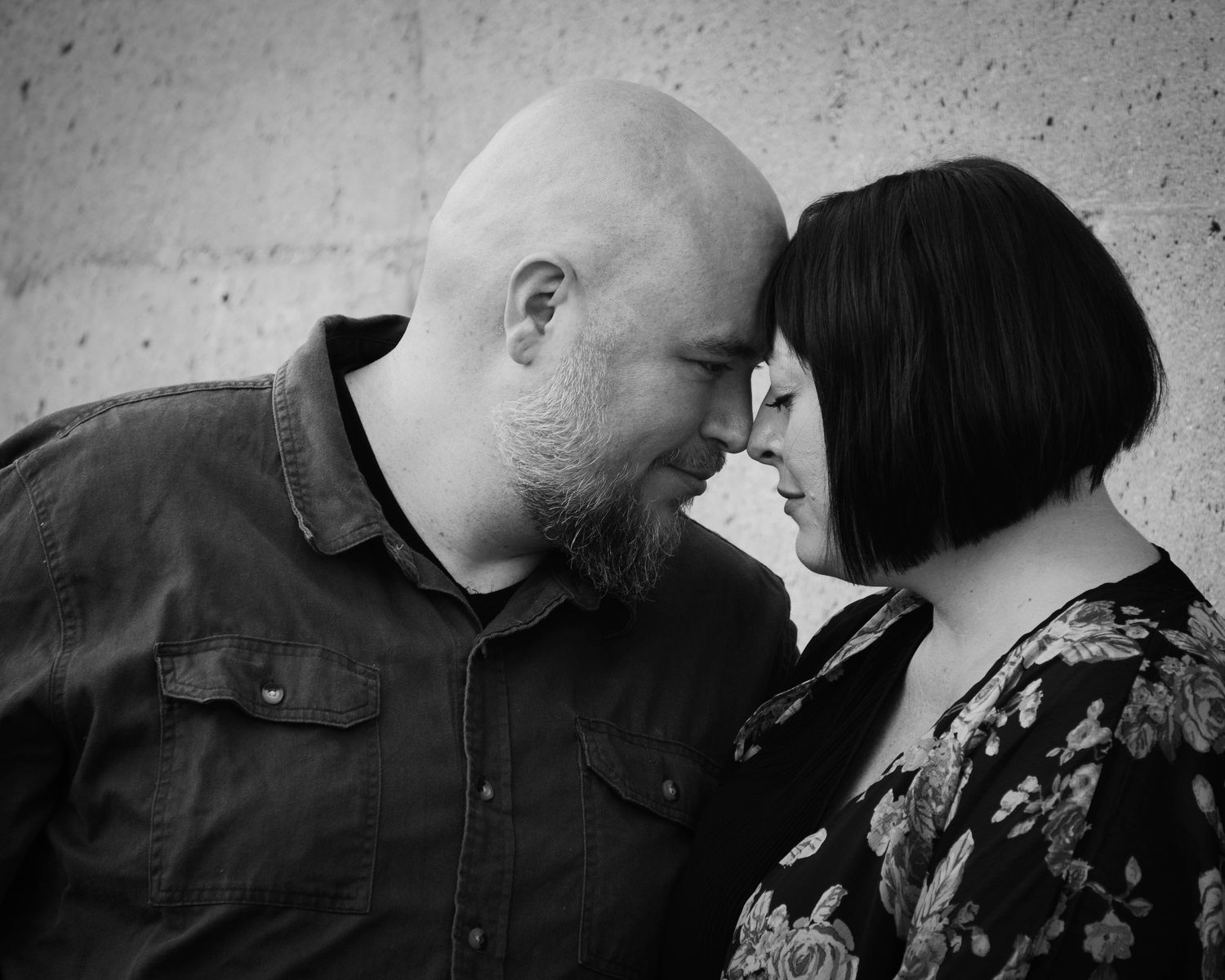 Black and white series of a couple sharing intimate moments against a textured wall.