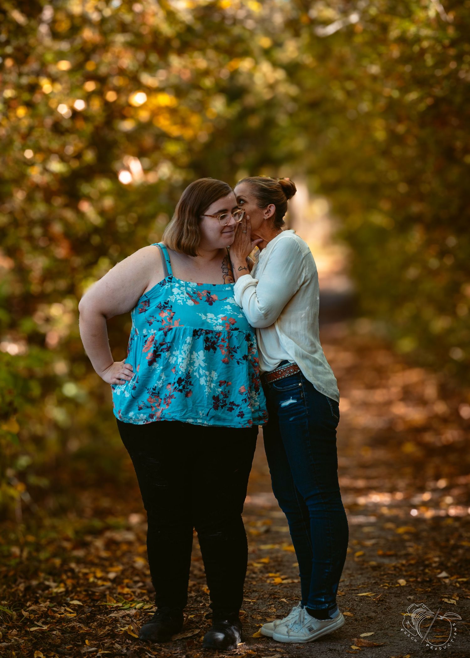 Two people share a tender moment on an autumn path surrounded by golden leaves.