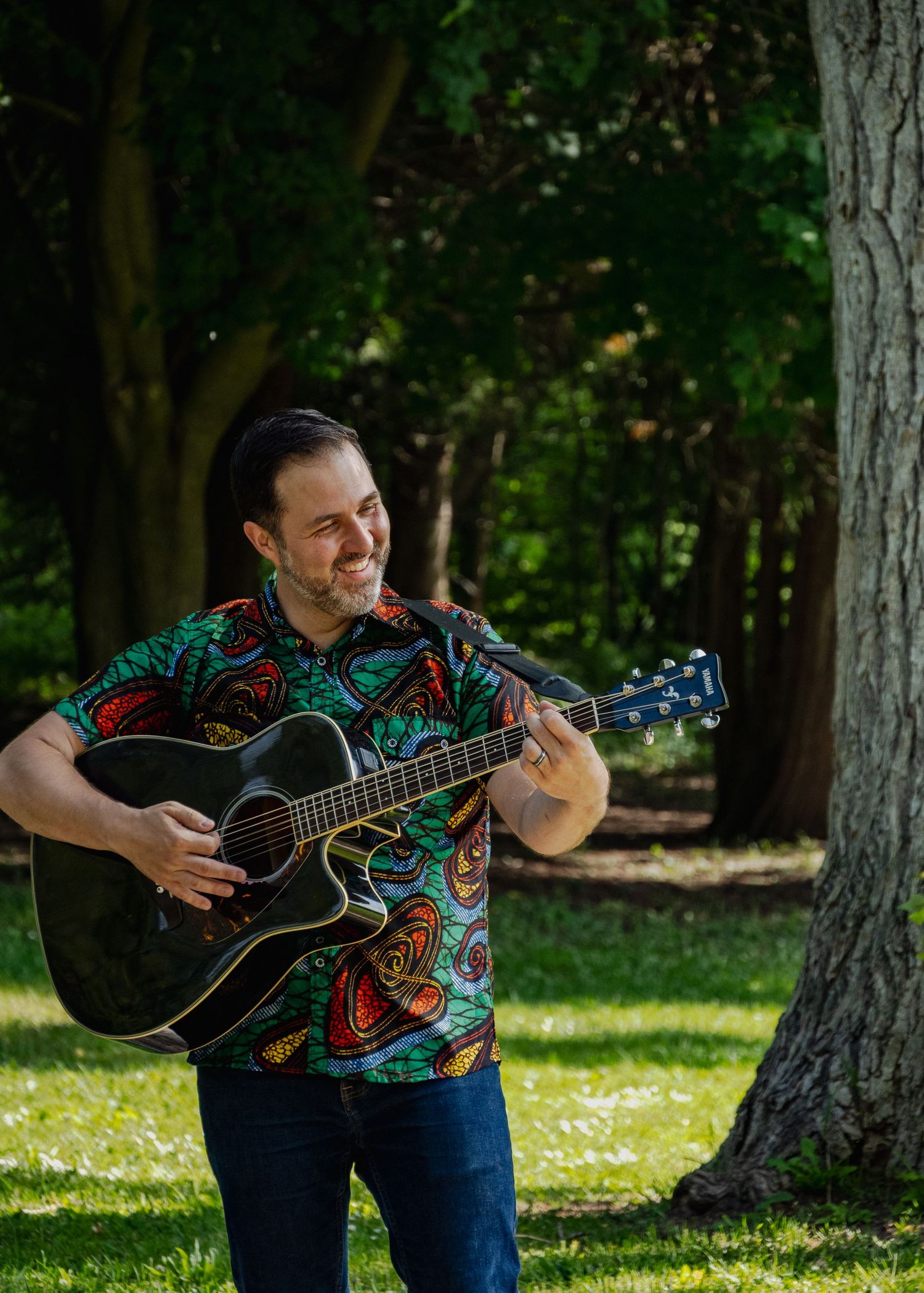 Series of shots showing guitarist performing outdoors among trees in a park.