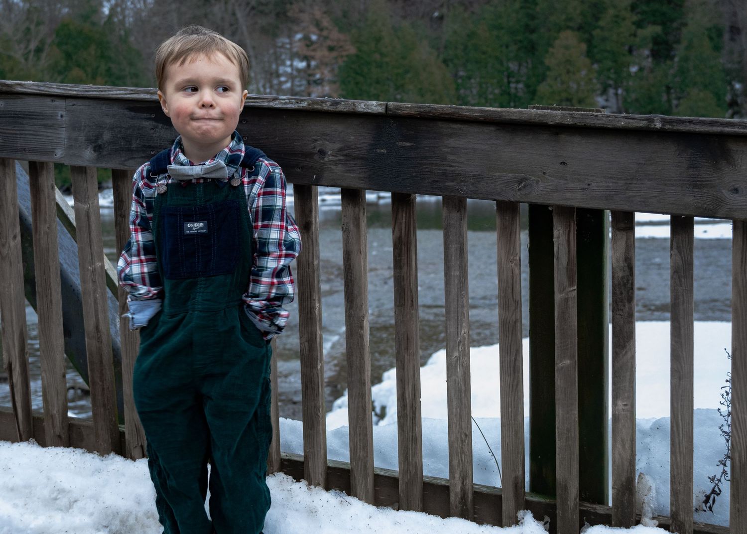 Winter portrait session on a wooden walkway with snow covered landscape in the background.