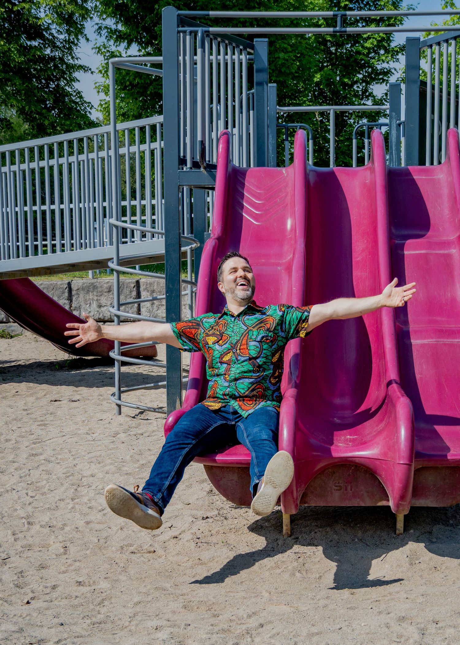 Playful sequence showing someone sliding down a pink playground slide in a colorful shirt.