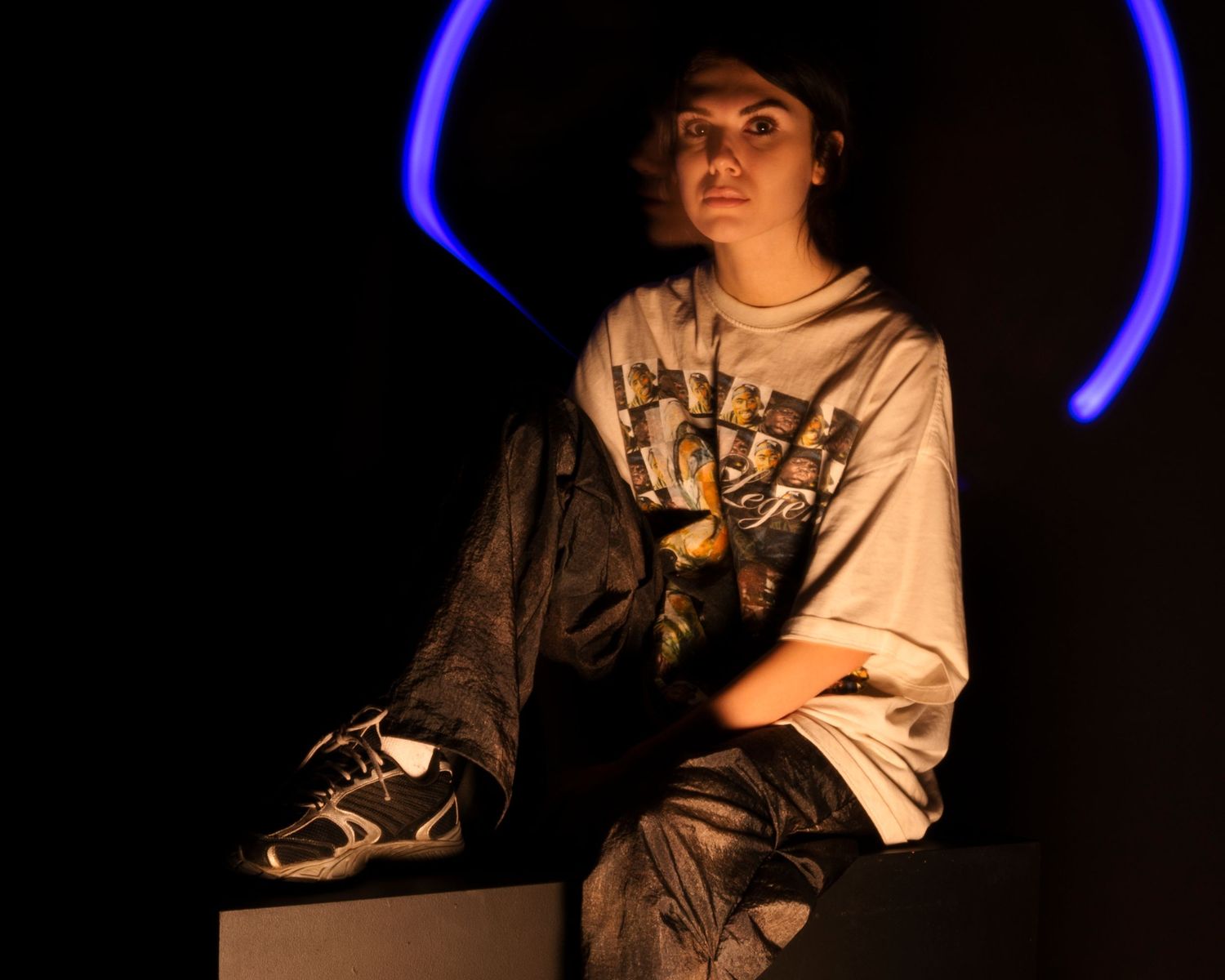 Dramatic low-key portrait with blue neon lighting and dark shadows creating a moody atmosphere.