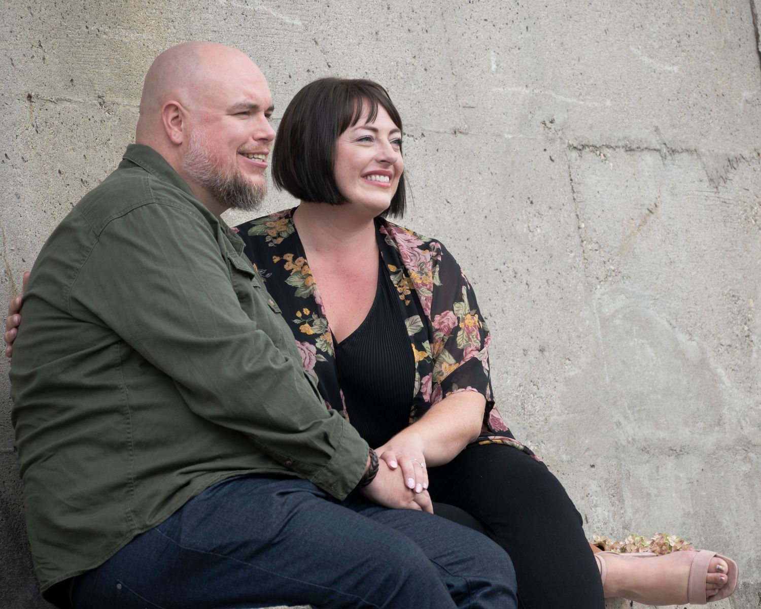 A couple relaxes on concrete steps sharing laughter and embraces.