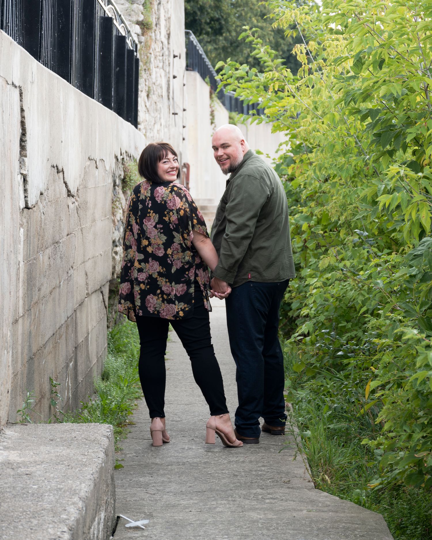 A couple shares a special moment on concrete steps surrounded by greenery.