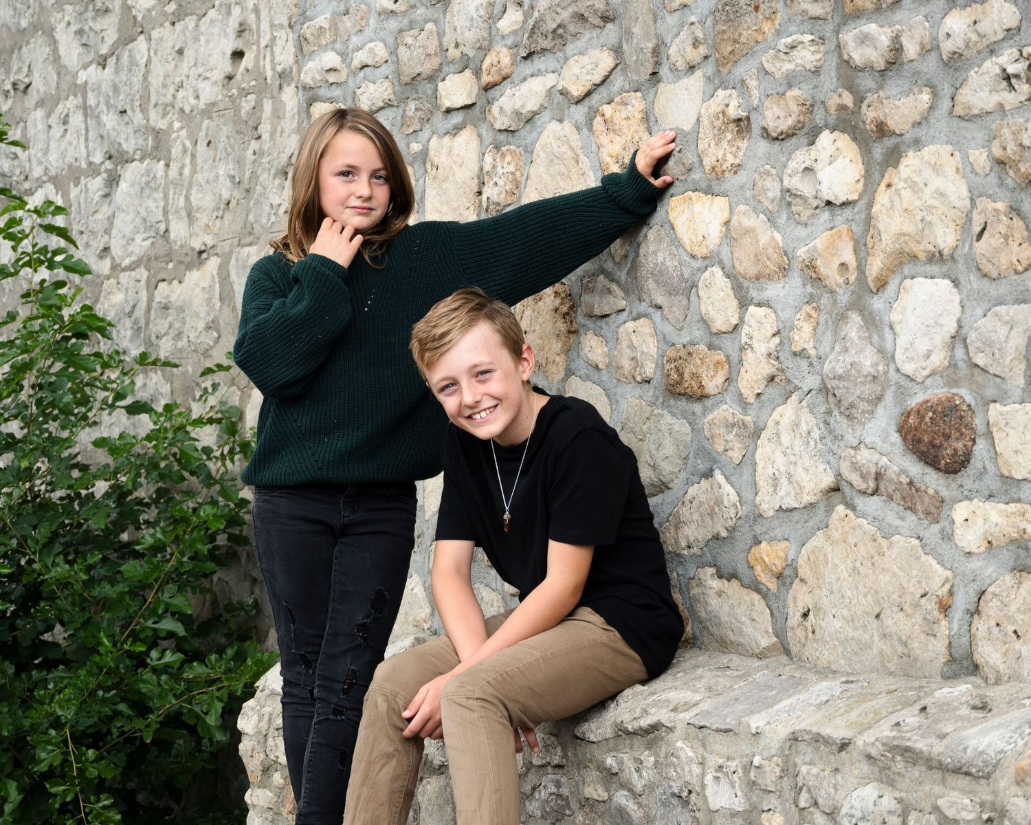 Candid portraits of people posing and laughing by a stone wall.