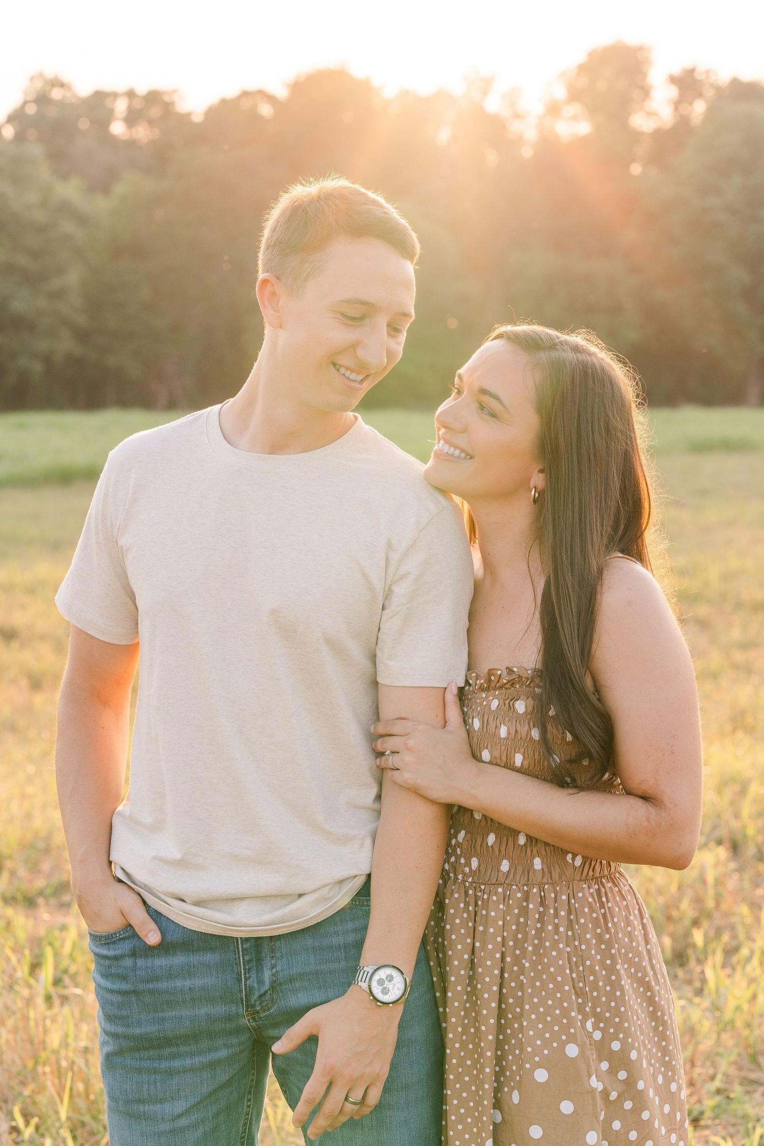 Greensboro, NC Couples Photographer, Ryan Harden, Reidsville NC, loving couple holds each other in a lush green field at sunset.