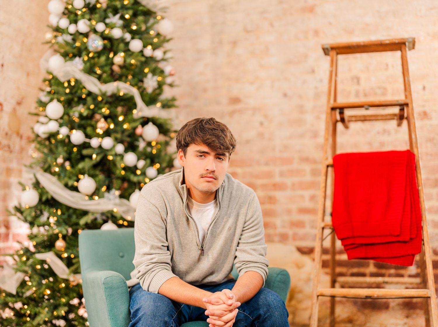Greensboro, NC Family Photographer, Ryan Harden, Reidsville NC, son poses in front of Christmas tree for seasonal session in studio.