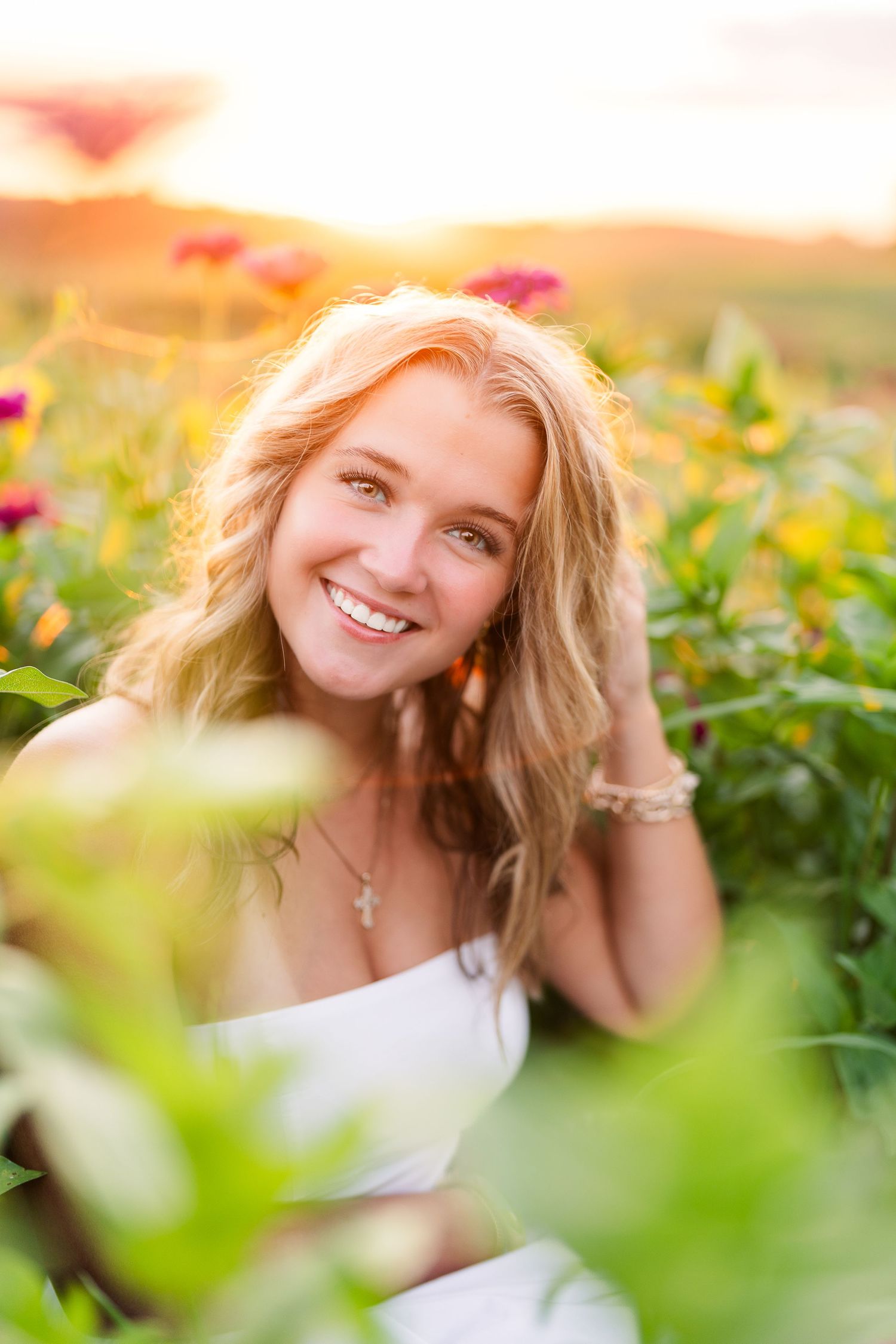 Greensboro, NC Senior Photographer, Reidsville, NC.  Ryan Harden. Stunning senior portrait  with girl in red flowers illuminated by sunlight