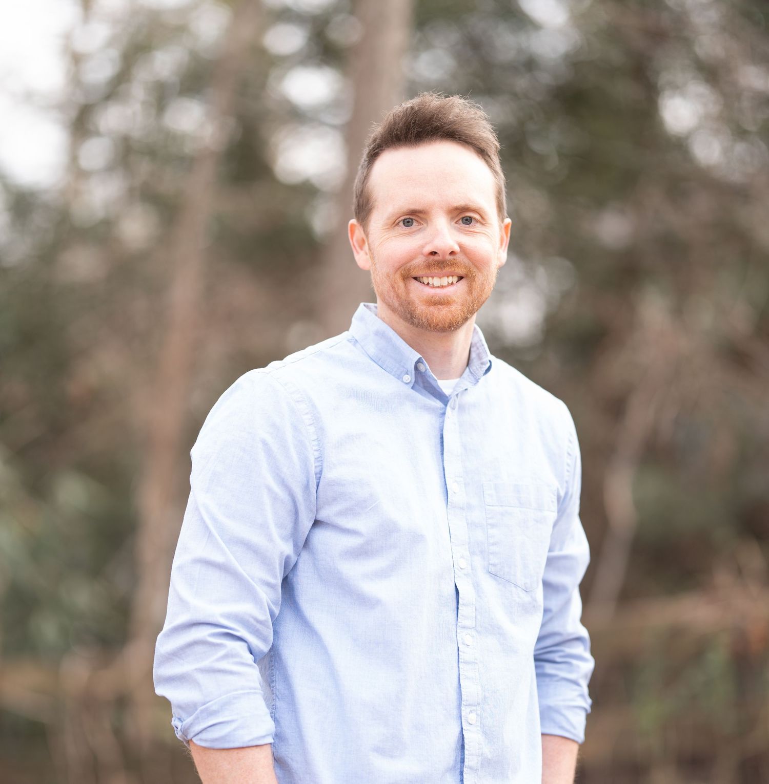 Greensboro, NC Family Photographer.  Senior Photographer.  Ryan Harden.  Reidsville, NC.  Ryan in blue button down shirt smiling with trees