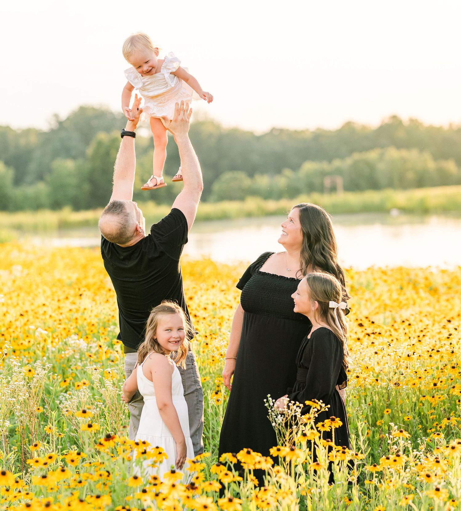 Greensboro, NC Family Photographer, Ryan Harden, Reidsville NC, happy family in field of daisies at sunset.  Dad tossing child in air.