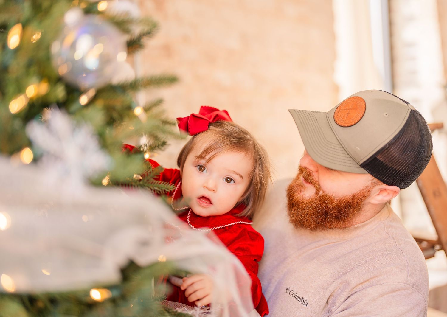 Greensboro, NC Family Photographer, Ryan Harden, Reidsville NC, dad holds little daughter at Christmas tree as they decorate it.