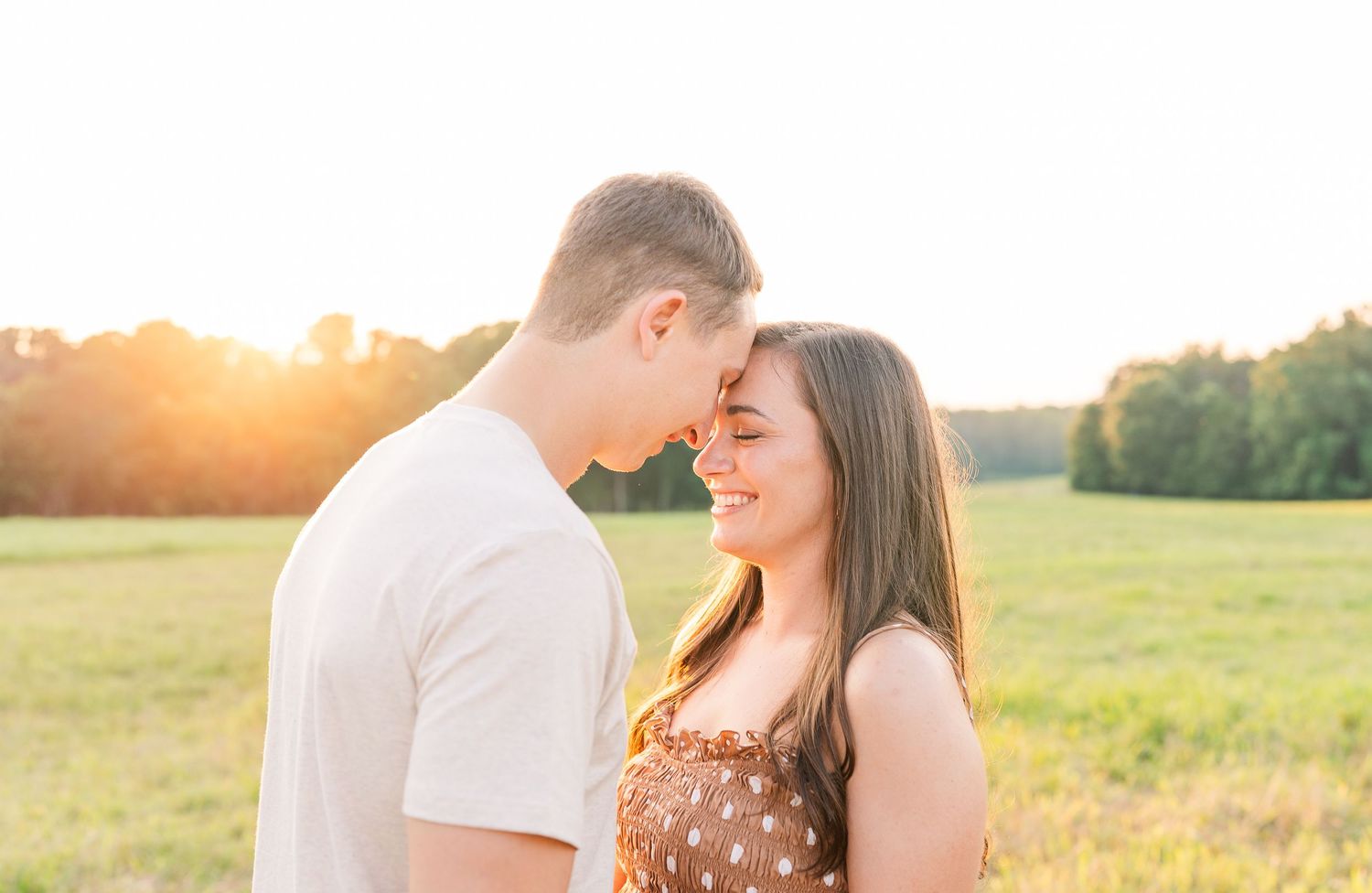 Greensboro, NC Couples Photographer, Ryan Harden, Reidsville NC, loving couple holds each other in a lush green field at sunset.