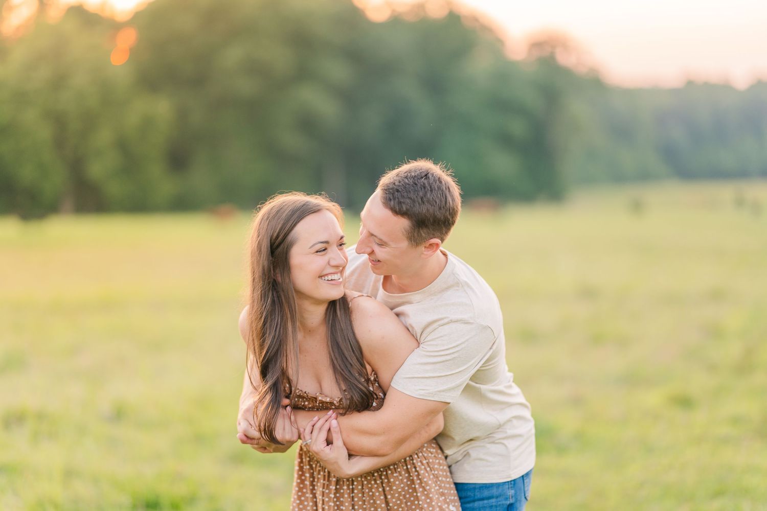 Greensboro, NC Couples Photographer, Ryan Harden, Reidsville NC, loving couple holds each other in a lush green field at sunset.