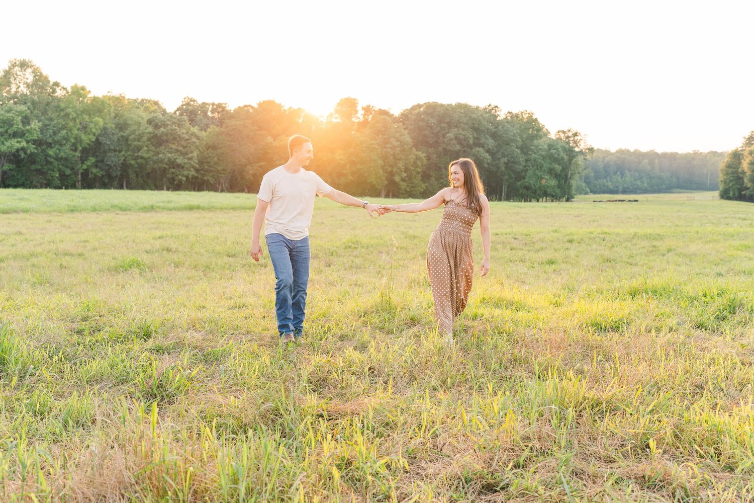 Greensboro, NC Couples Photographer, Ryan Harden, Reidsville NC, loving couple holds hands in a lush green field at sunset.