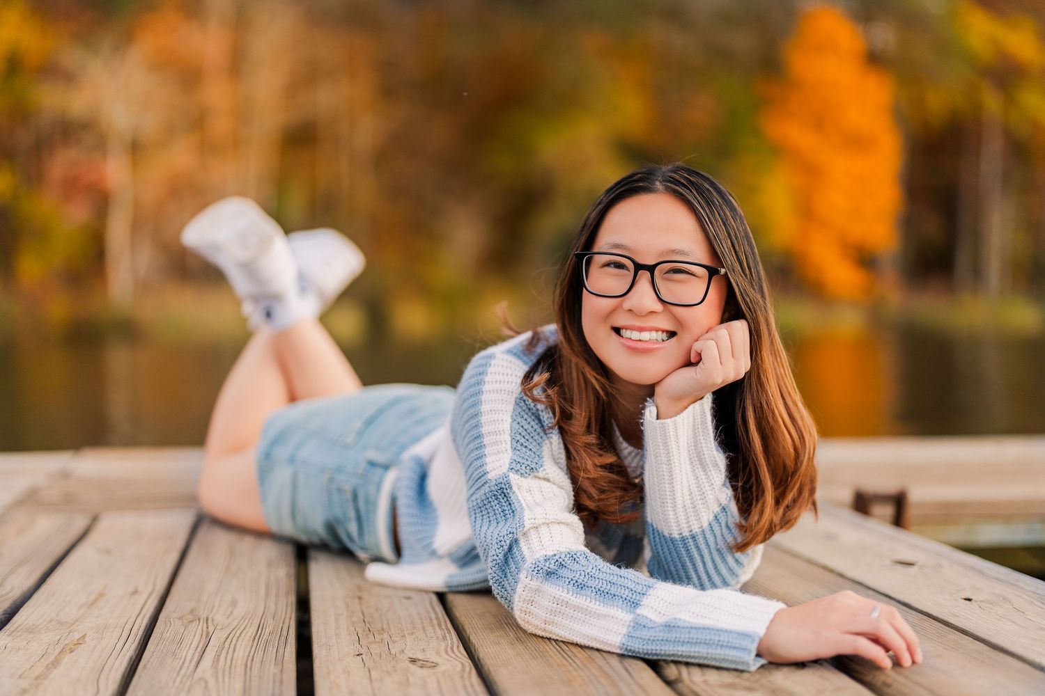 Greensboro, NC Senior Photographer, Reidsville, NC.  Ryan Harden.  stunning portrait of girl on a lake dock with fall leaves behind her.