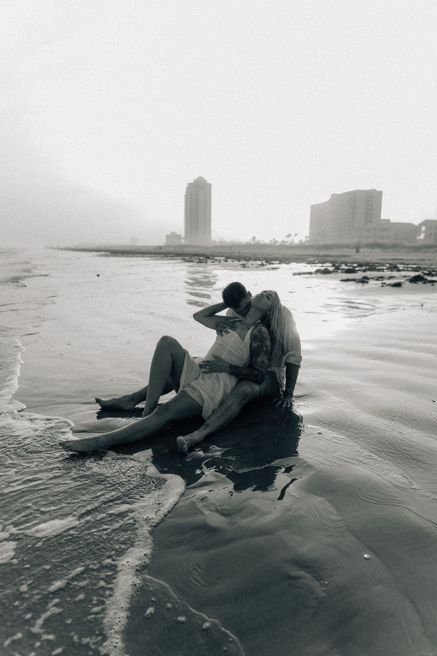 Artistic black and white beach series with city skyline visible in background.