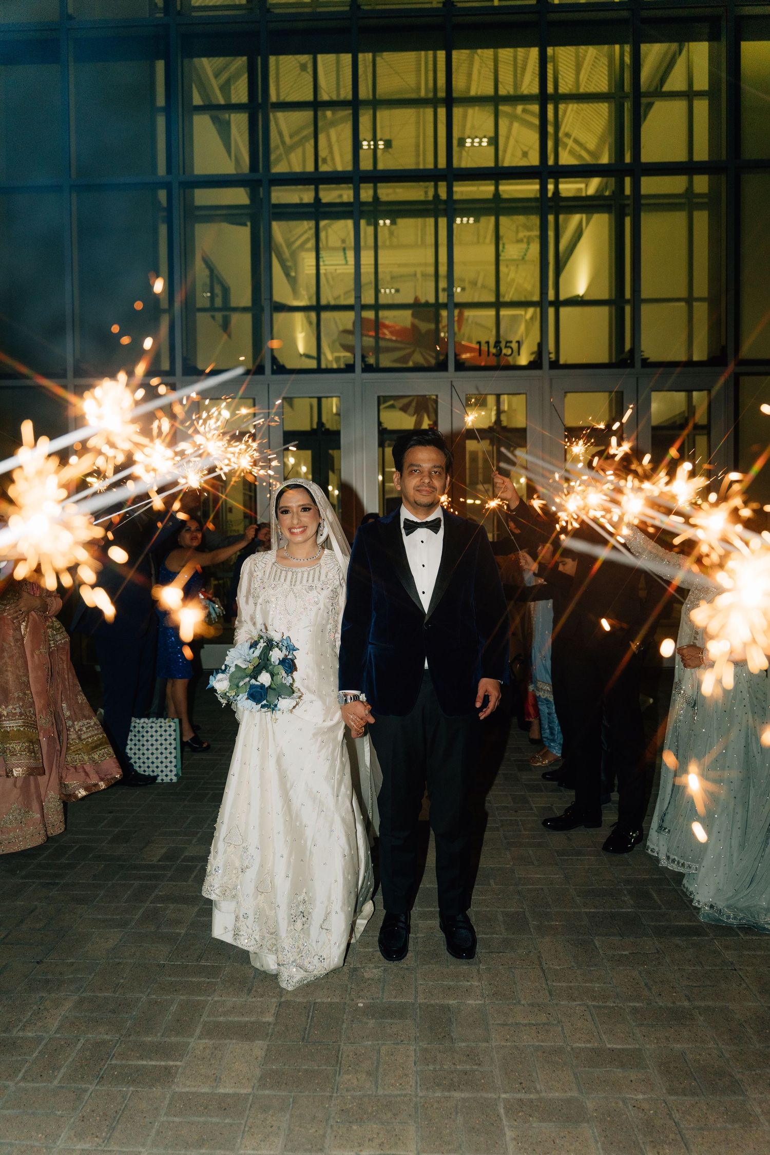 Wedding guests holding sparklers creating a magical exit pathway at night.