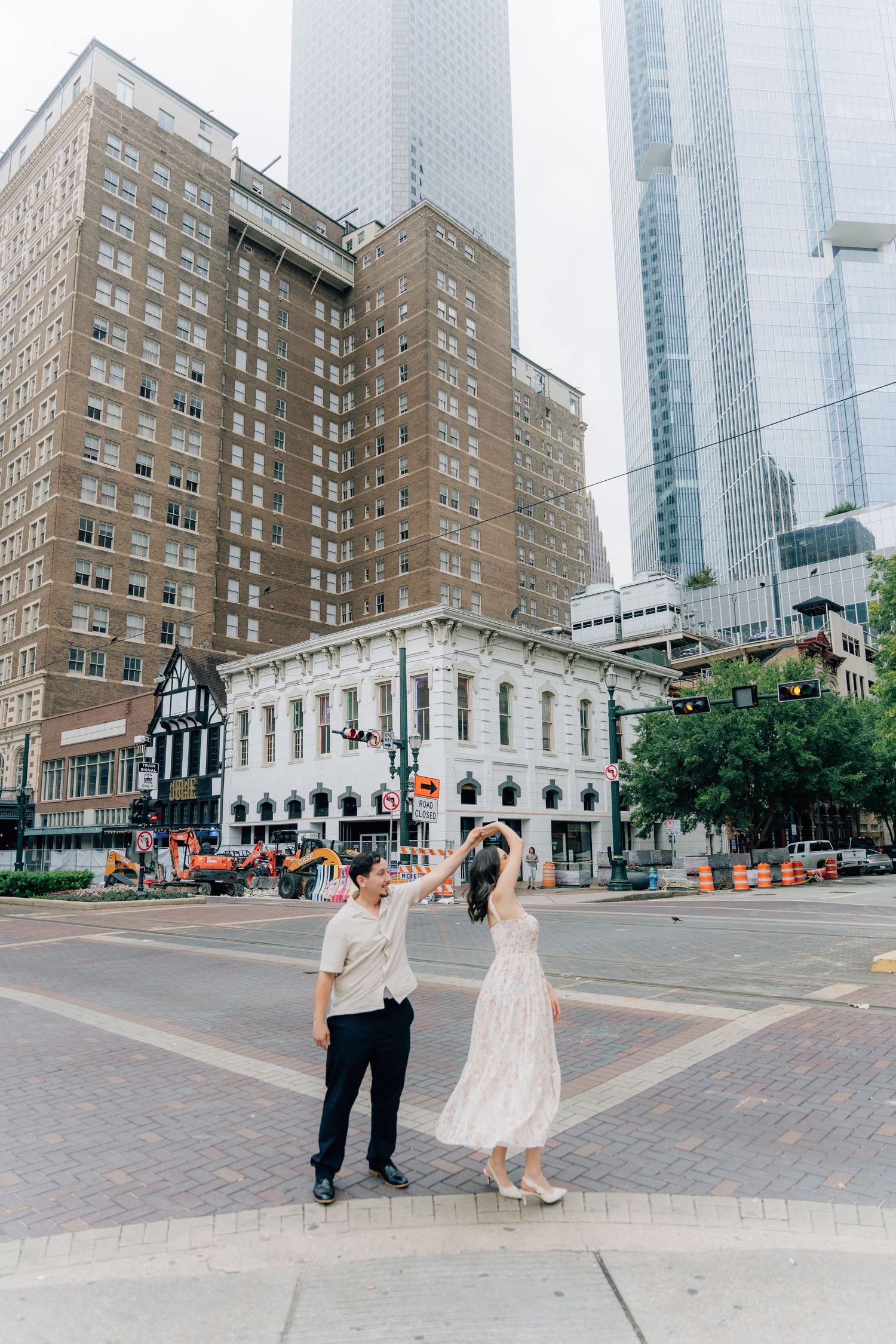 A couple dancing on a city street corner with historic architecture and modern skyscrapers in downtown Austin, Texas.