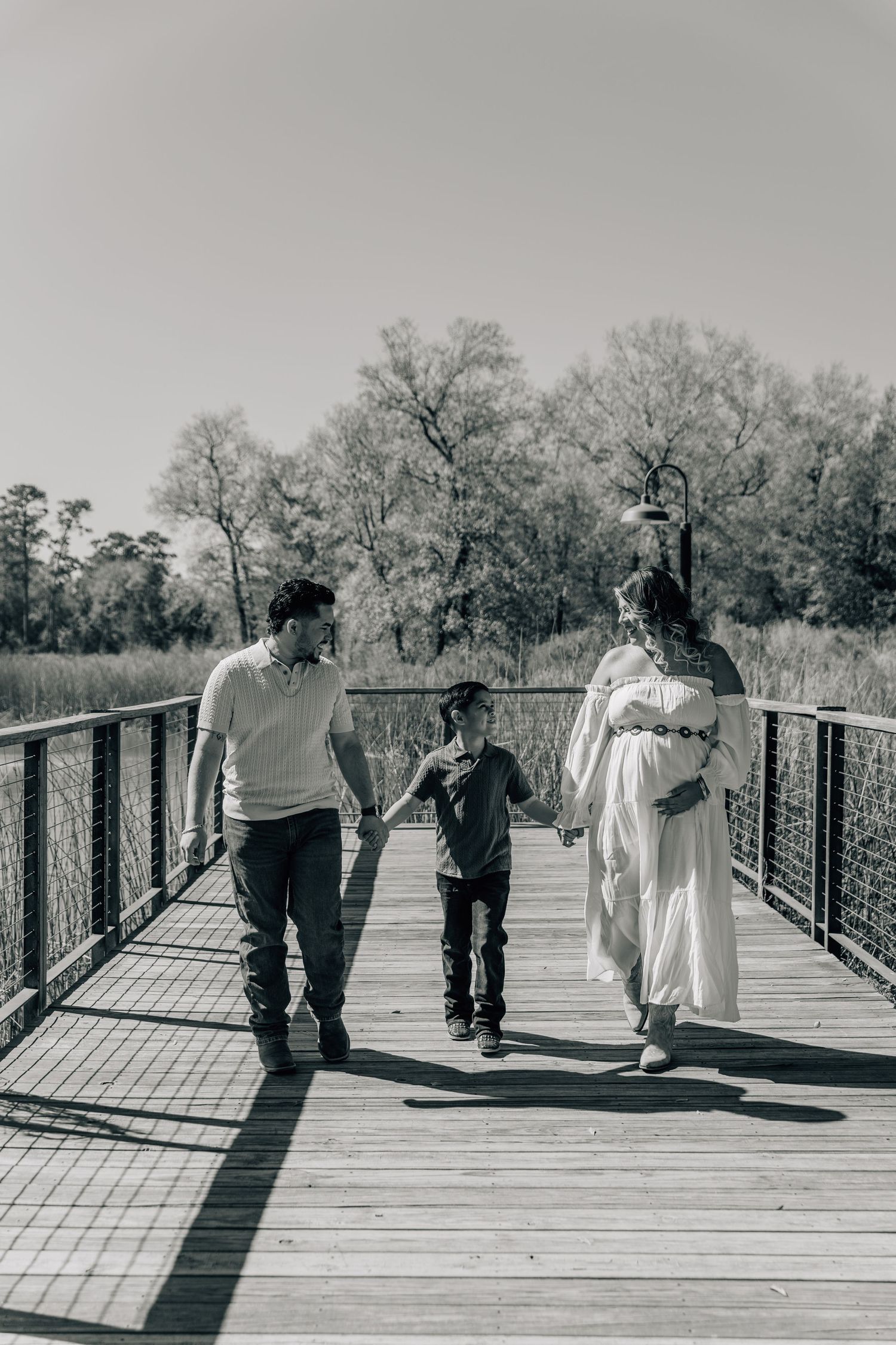 Black and white series of people walking on a wooden bridge with shadows.