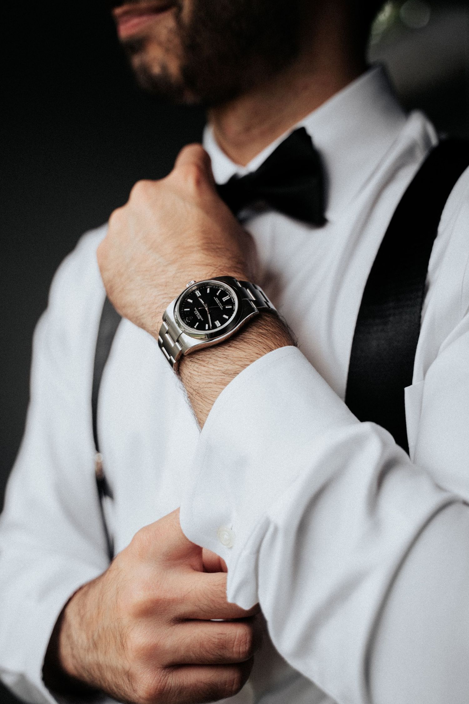 Close-up shots of groom adjusting formal attire and watch before ceremony.