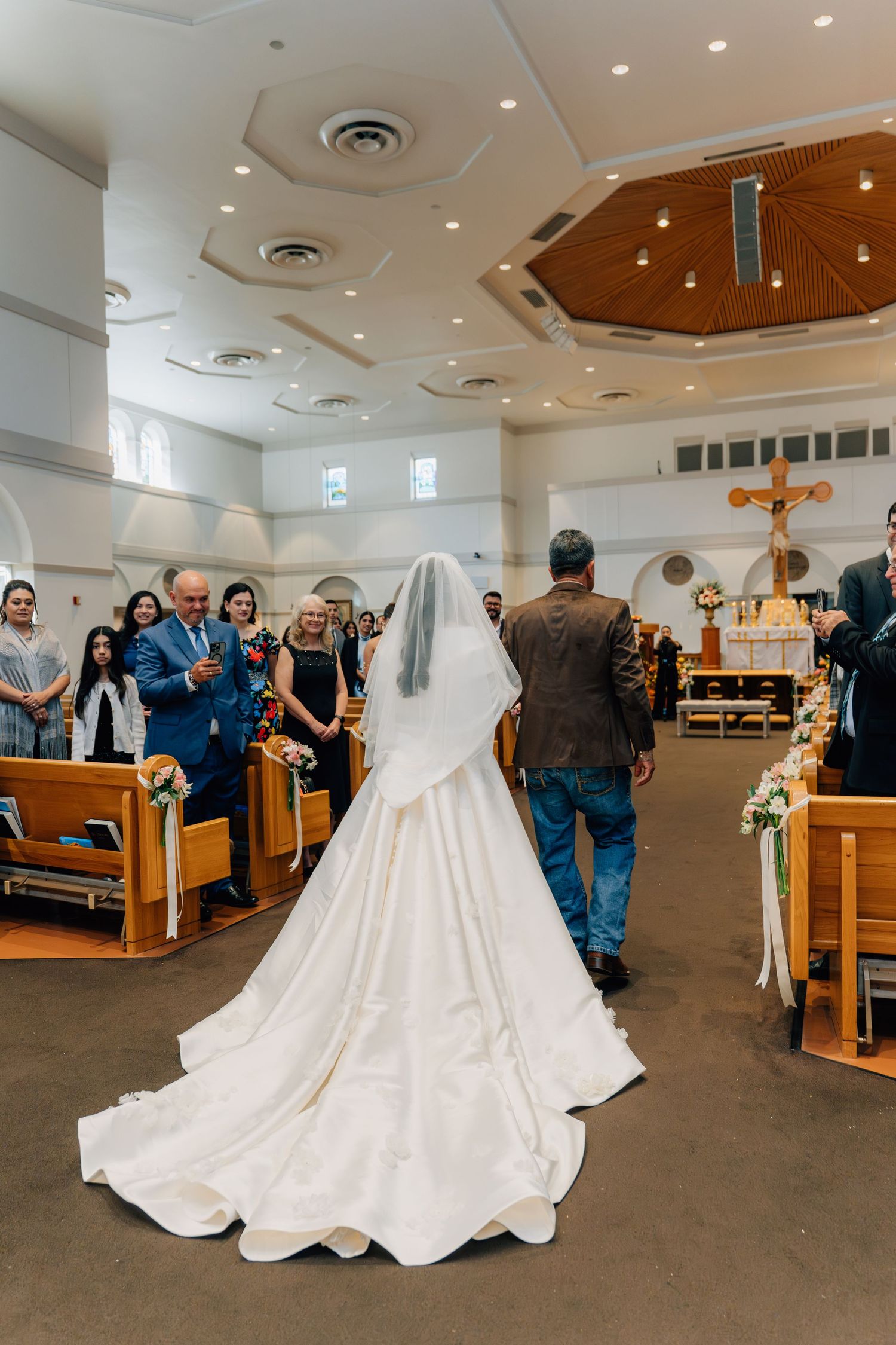 Wedding celebration in church with guests lining the aisle during ceremony.
