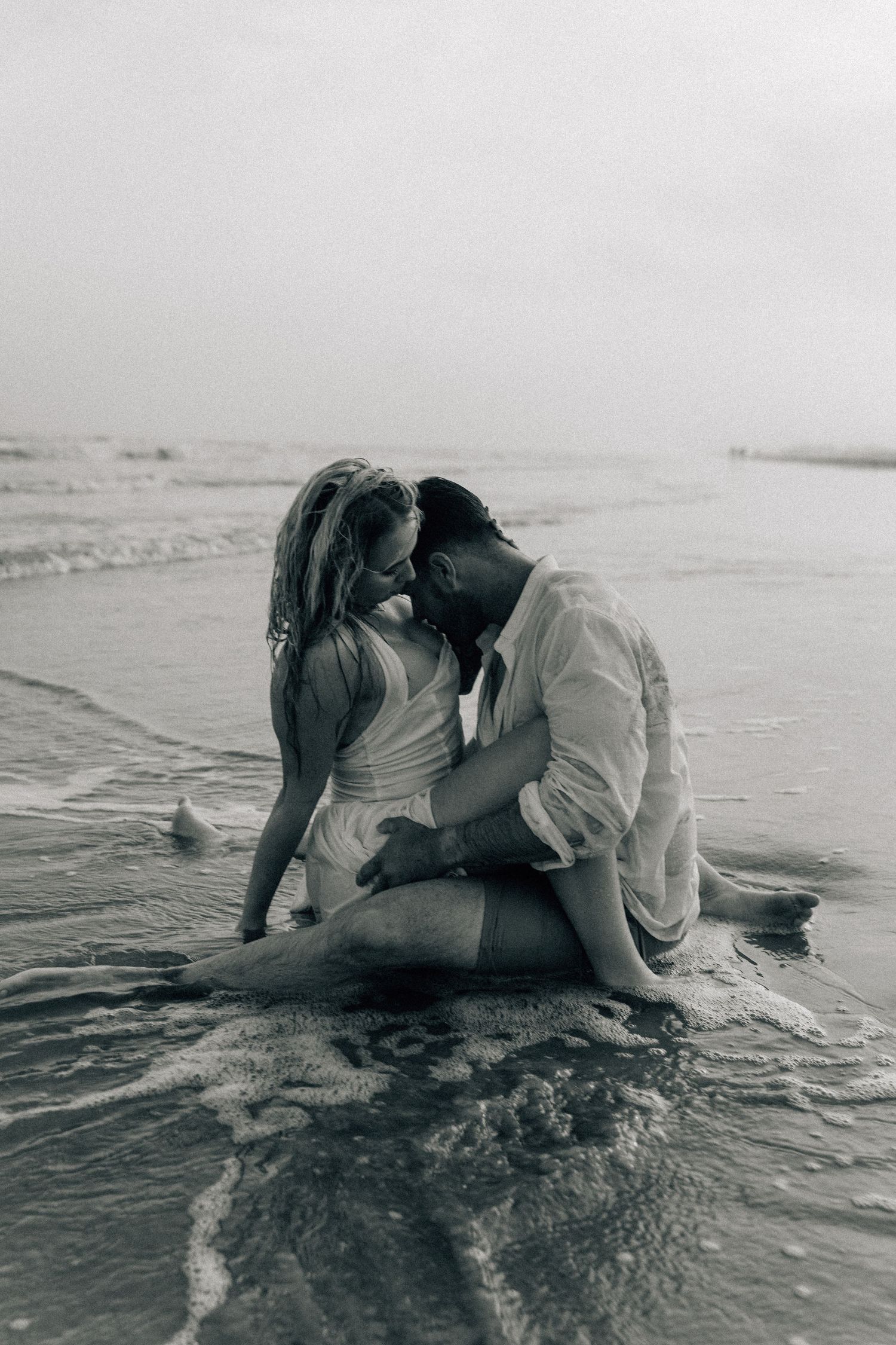 Romantic black and white sequence of couple embracing in ocean waves.