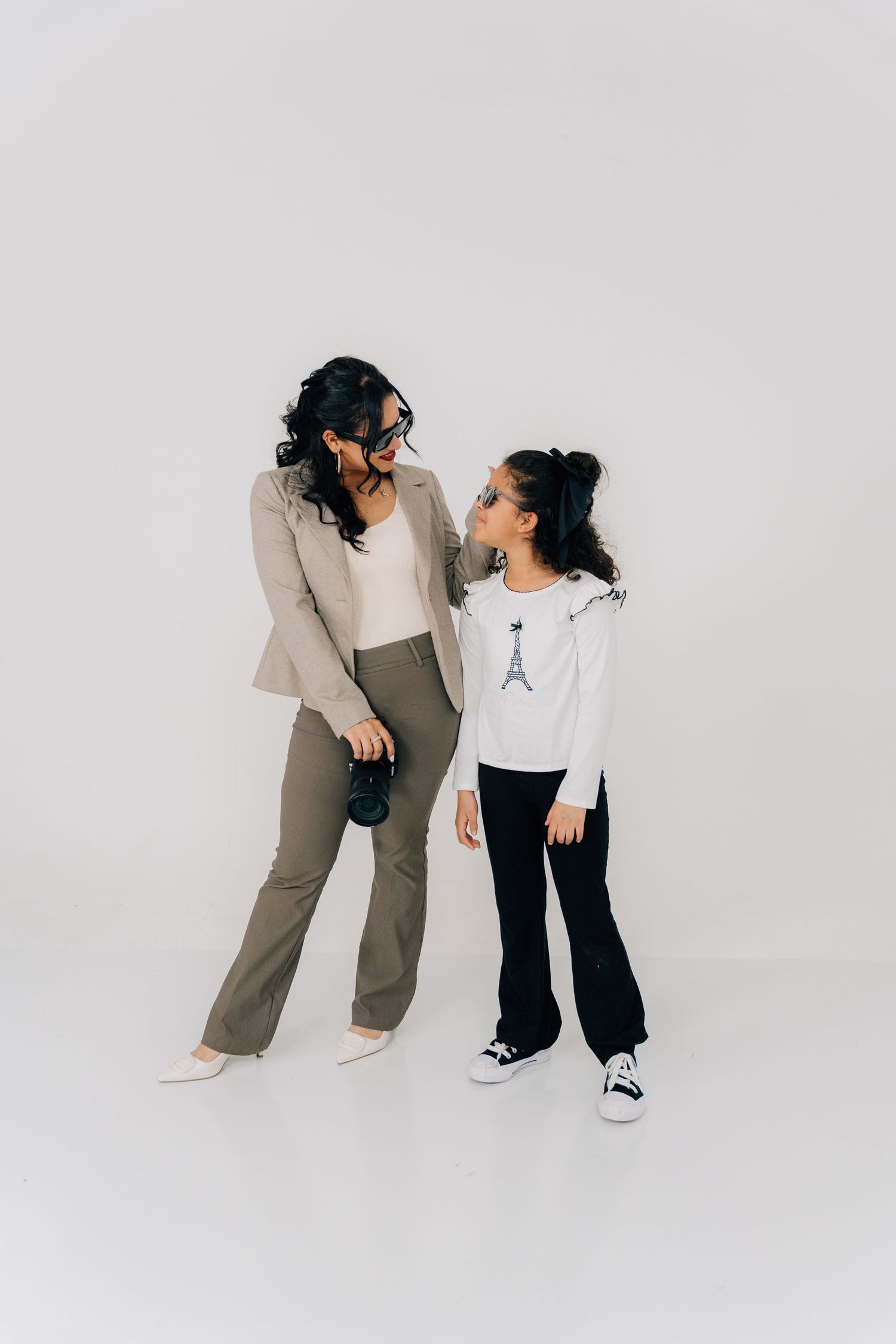Minimalist studio portraits showing two people in casual outfits dancing and interacting against white background.