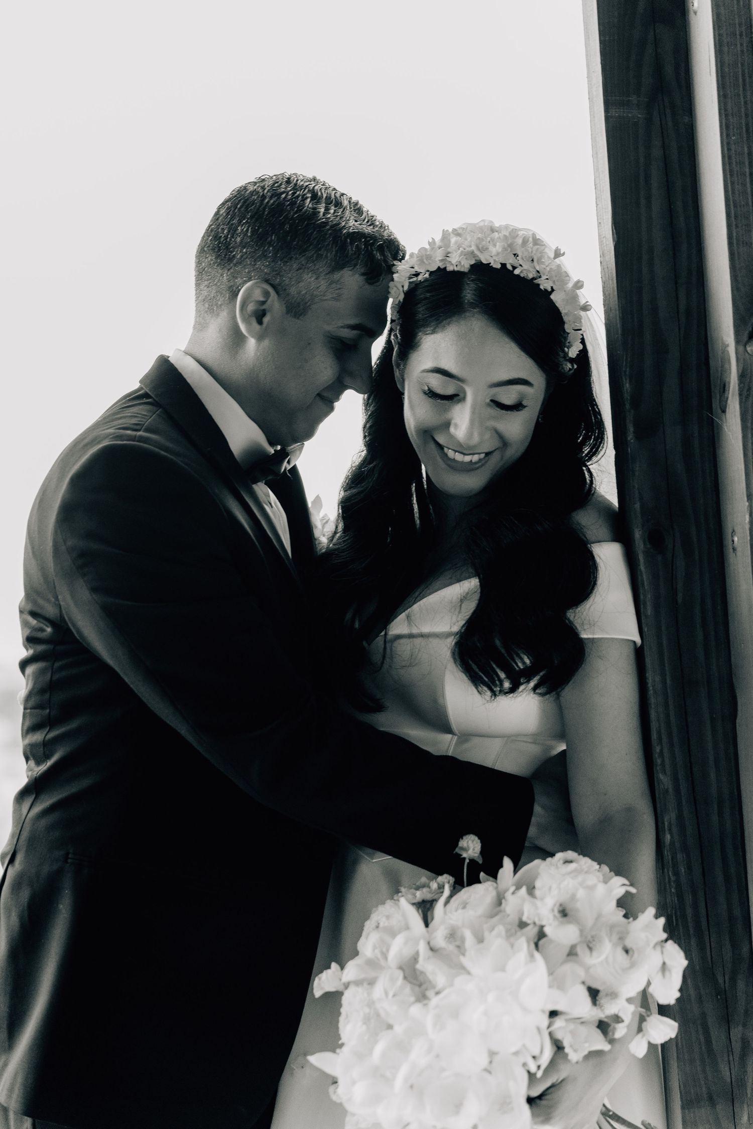 Romantic black and white wedding portraits showing tender moments between newlyweds with white floral bouquet.