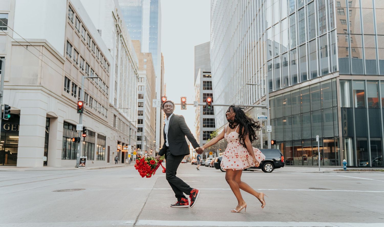 Urban engagement session showing playful couple running through modern city architecture.