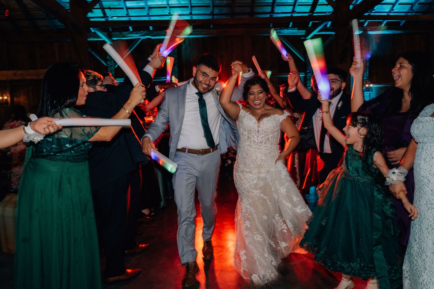 Wedding reception dance floor filled with guests dancing under colorful party lights.