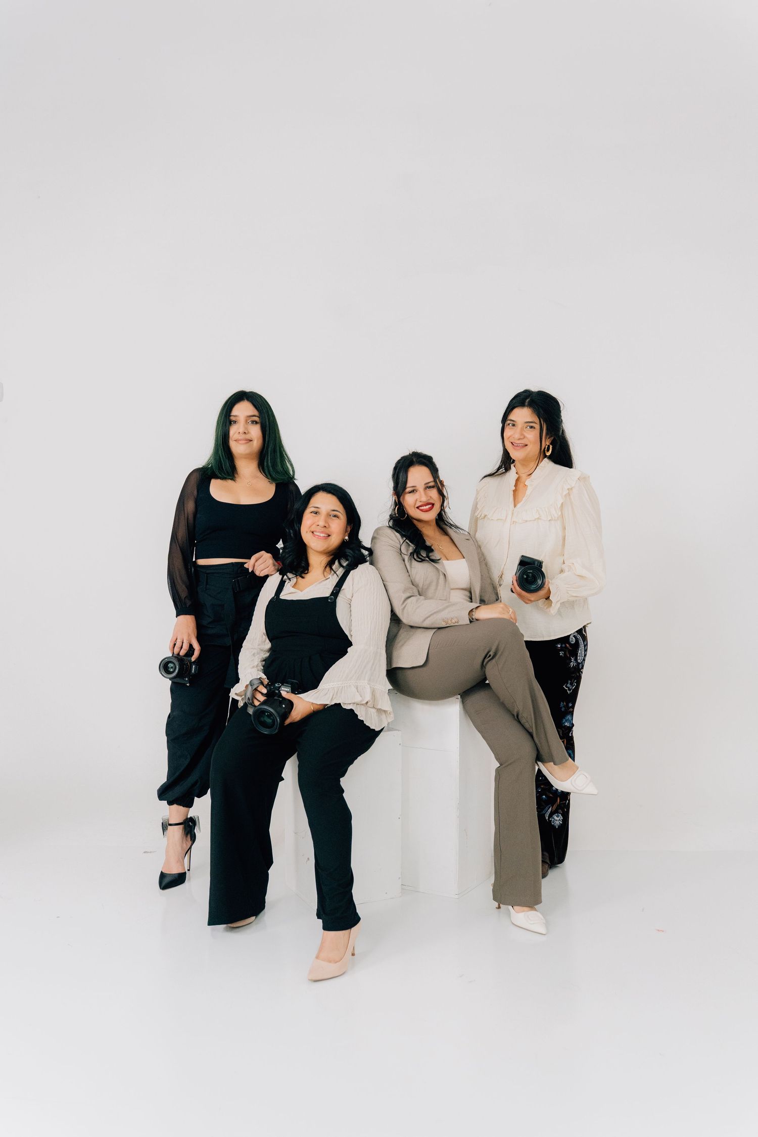 Professional group portrait with cameras in coordinated neutral-toned outfits.
