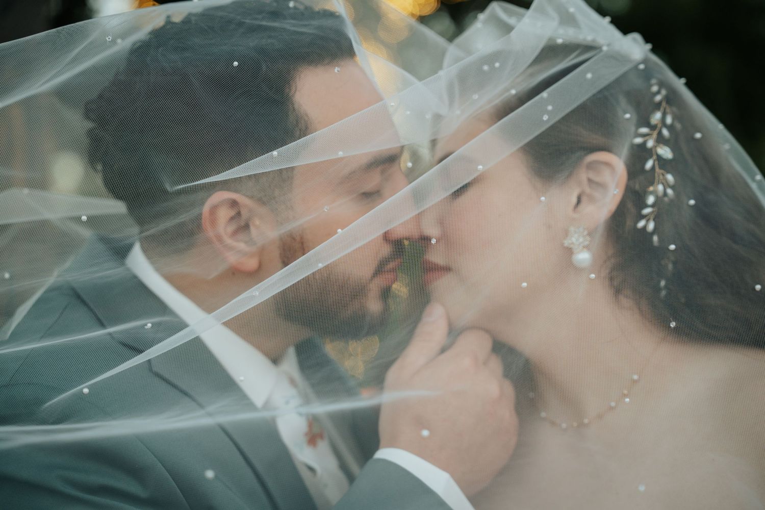 Romantic wedding portrait series showing couple sharing intimate moments under a delicate veil.