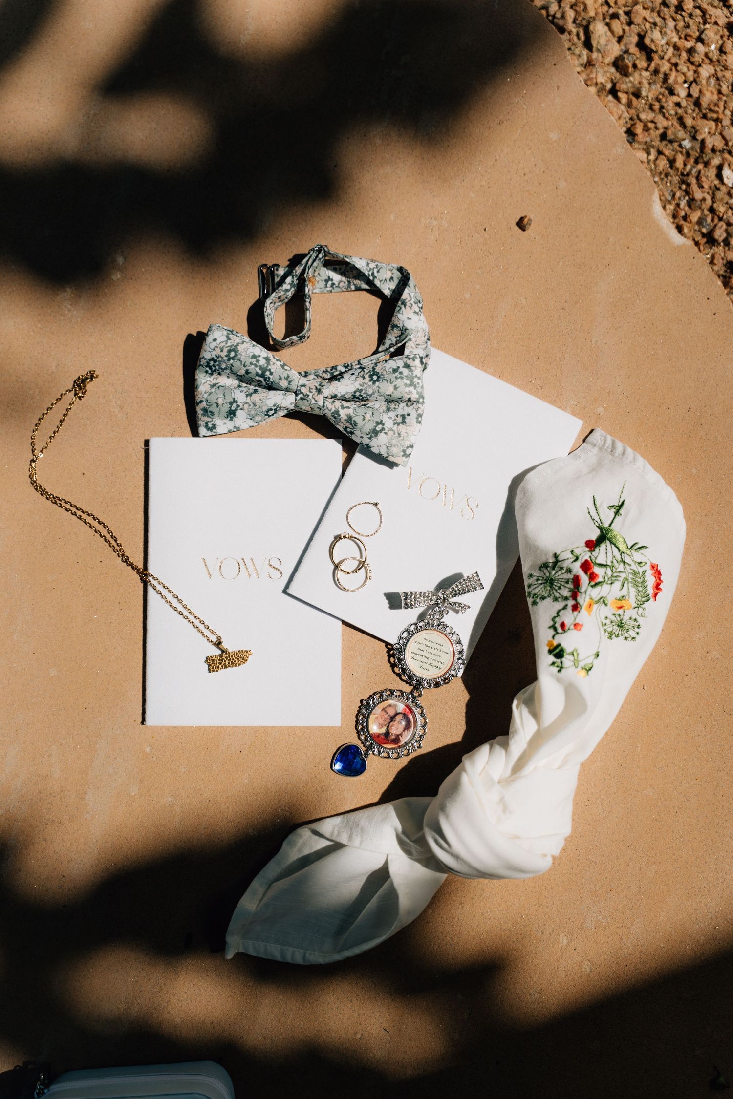 Wedding accessories and jewelry arranged on a textured beige surface with dramatic shadows.