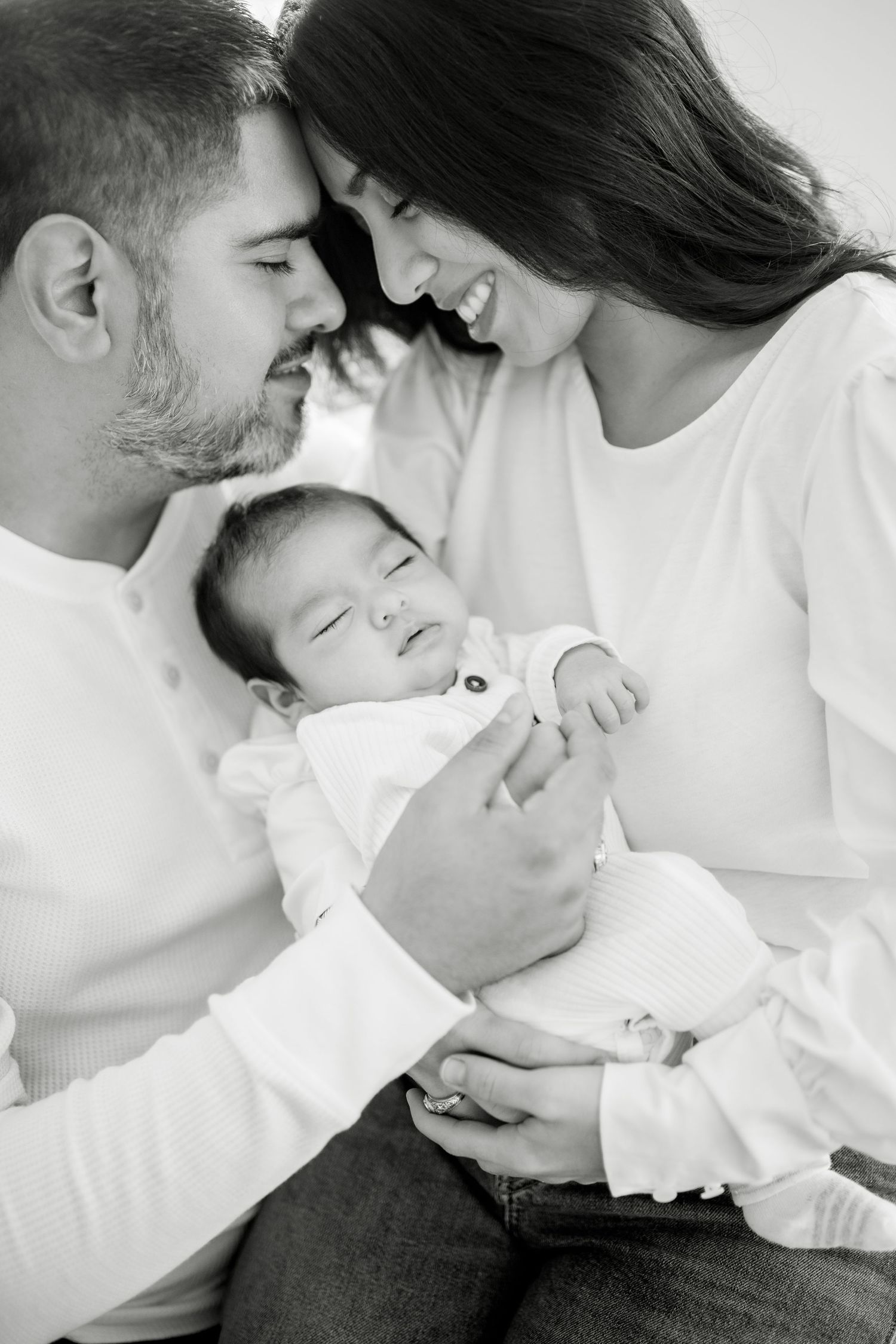 Intimate black and white family portrait session with newborn baby in white clothing.