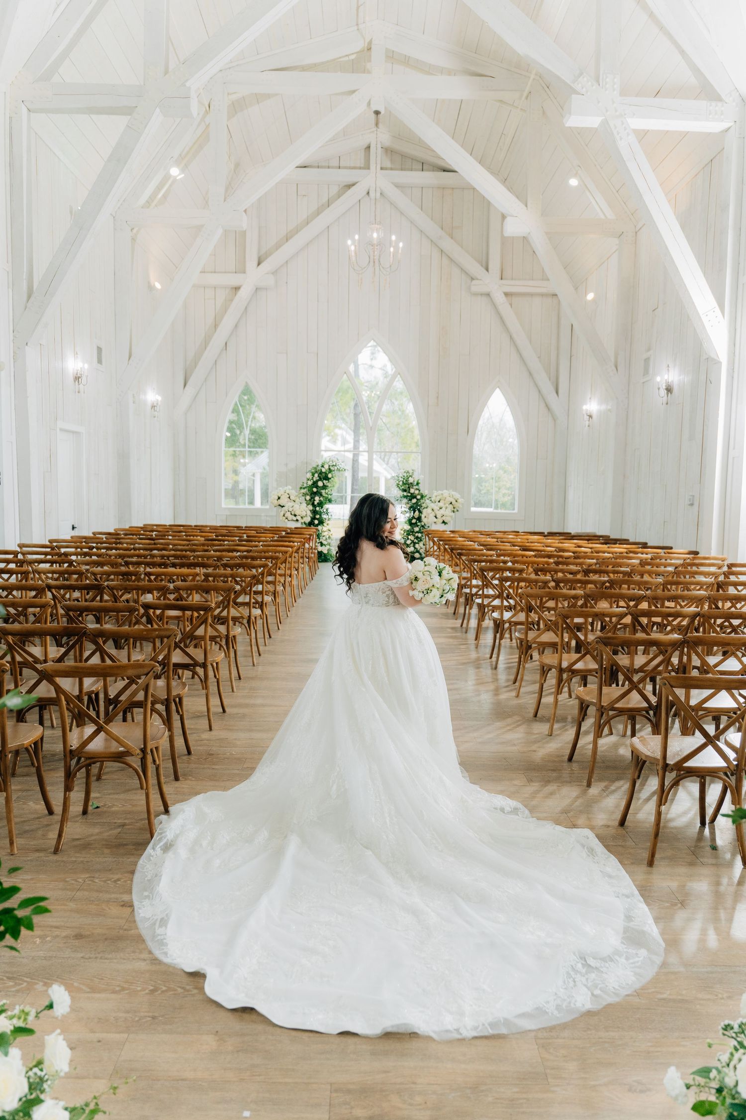White chapel interior with wooden cross-back chairs arranged for a wedding ceremony.