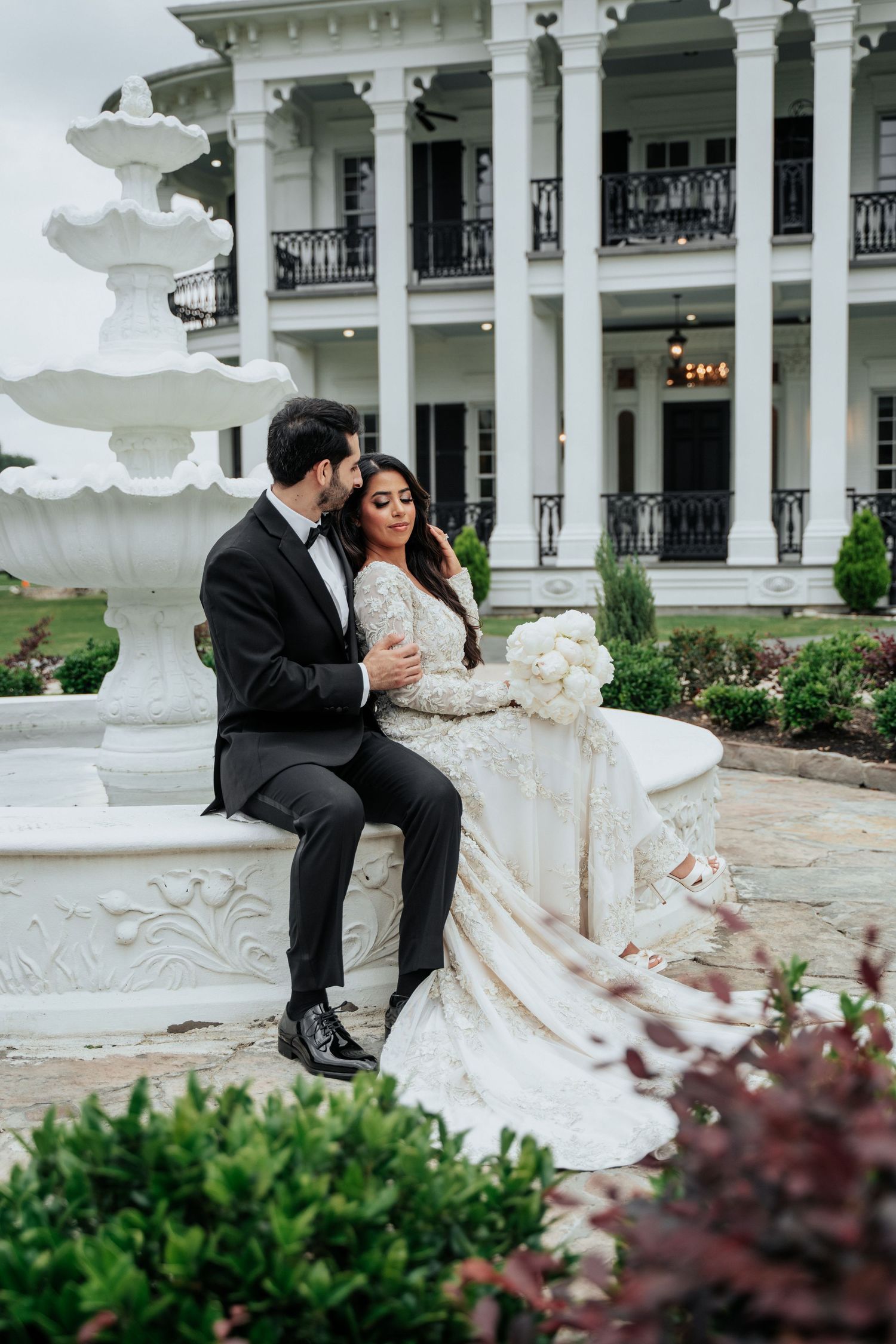 Classic white columned mansion provides an elegant backdrop for a wedding photoshoot.