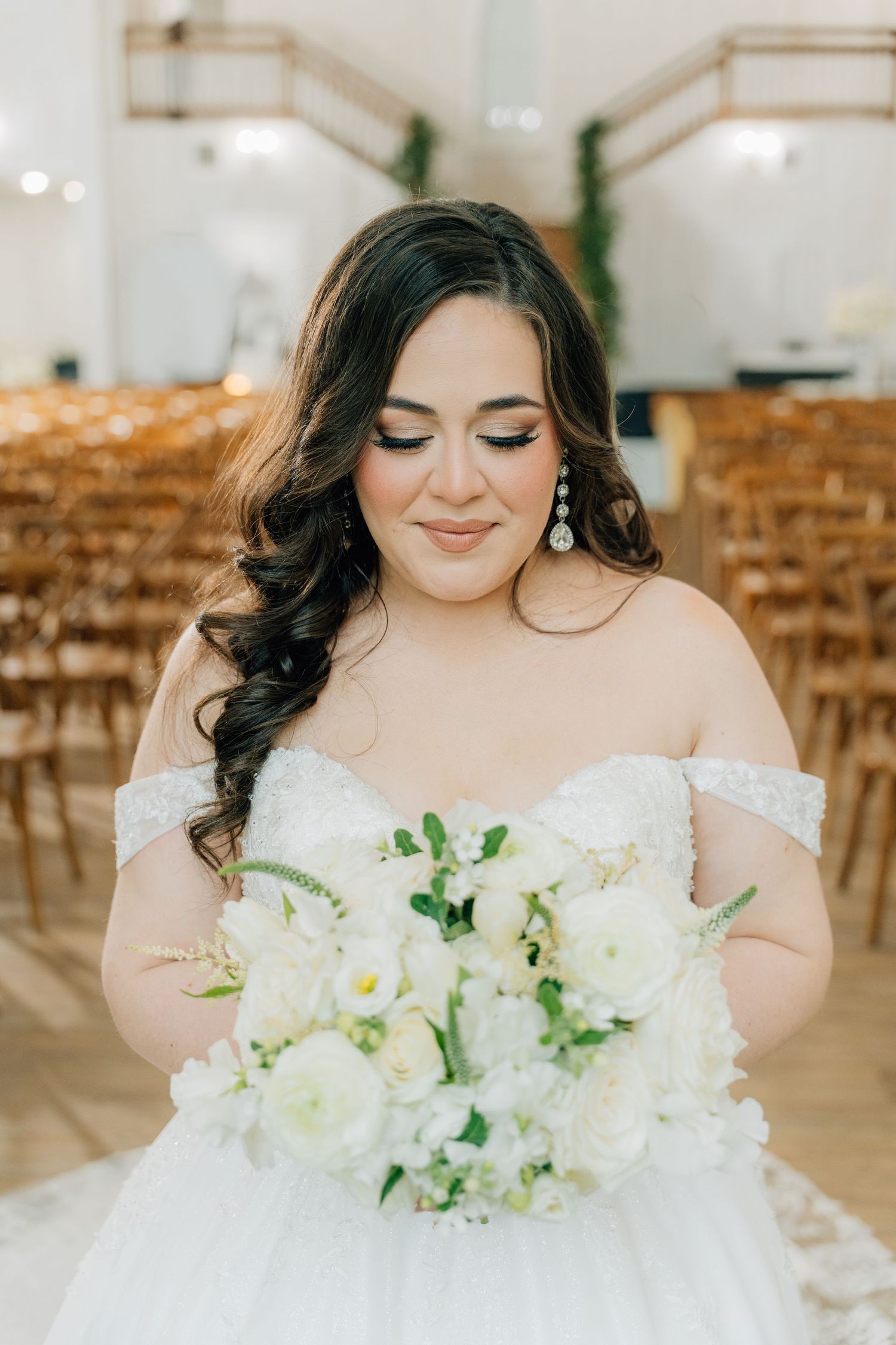 Beautiful white floral bouquet with cascading greenery against a white dress.