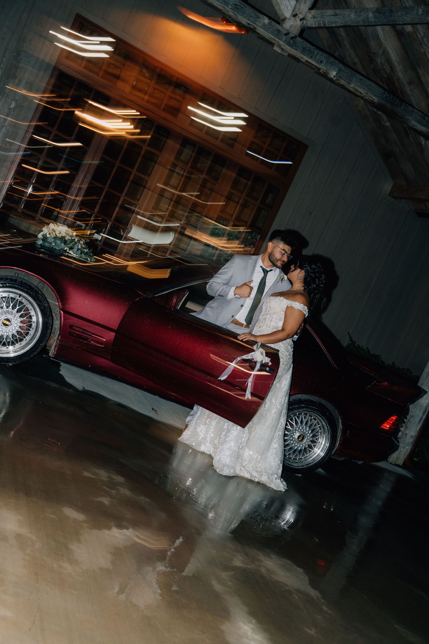 Couple sharing a romantic dance moment in a dimly lit parking garage with a vintage car in the background.