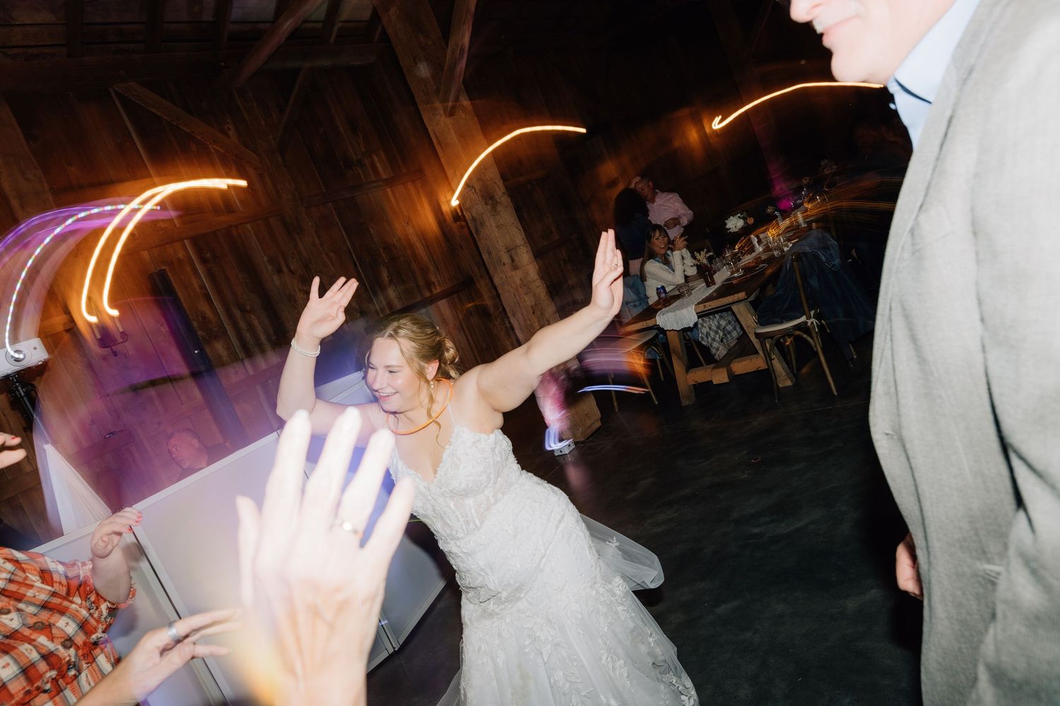 Wedding guests dancing and celebrating on a dimly lit dance floor.