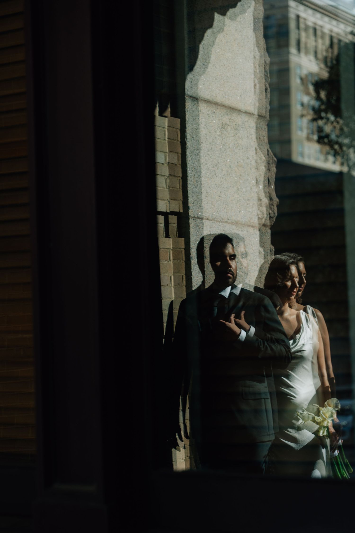 Dramatic shadows and light create an artistic wedding portrait against a building.