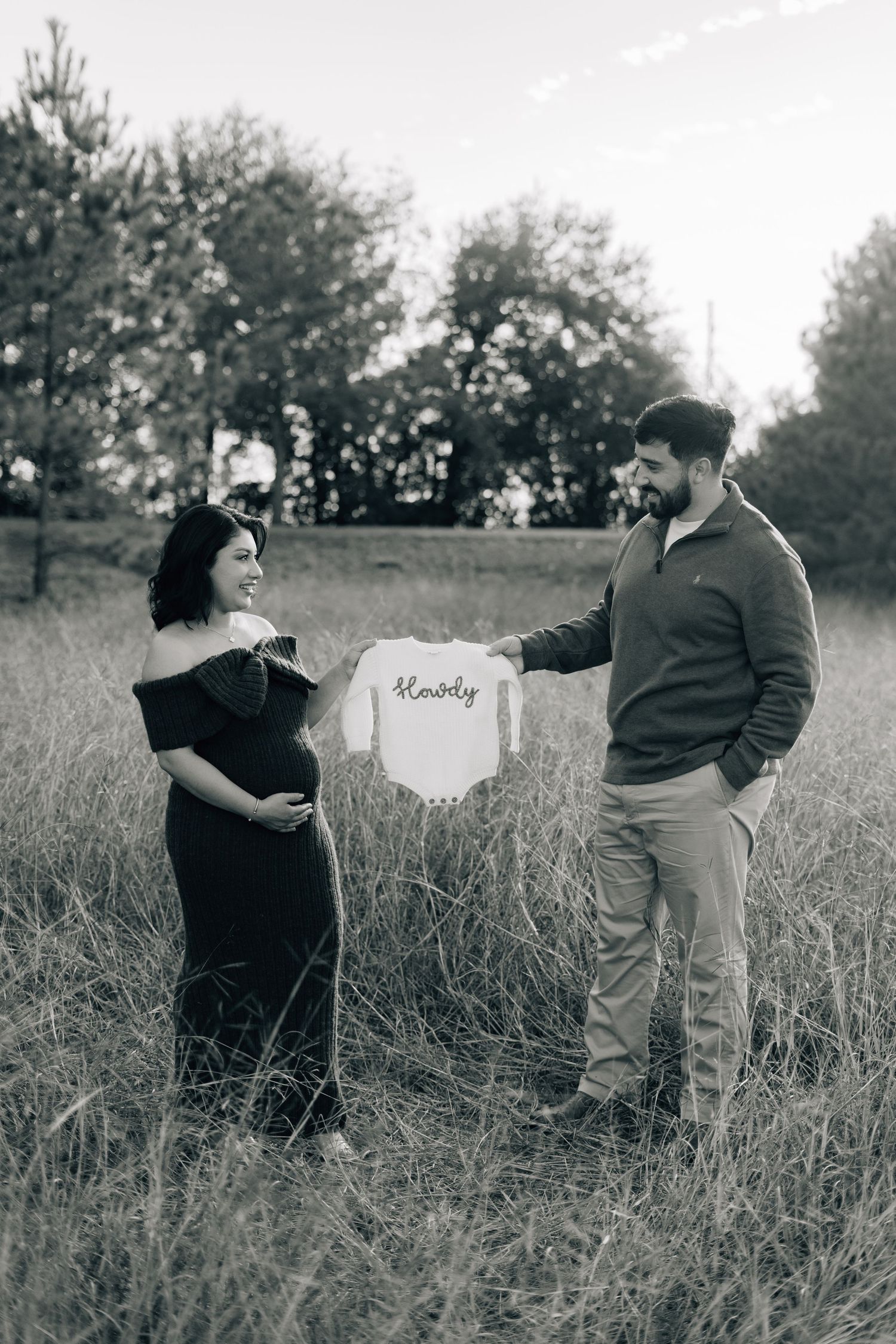 Black and white sequence showing couple posing with a sign in a grassy field.