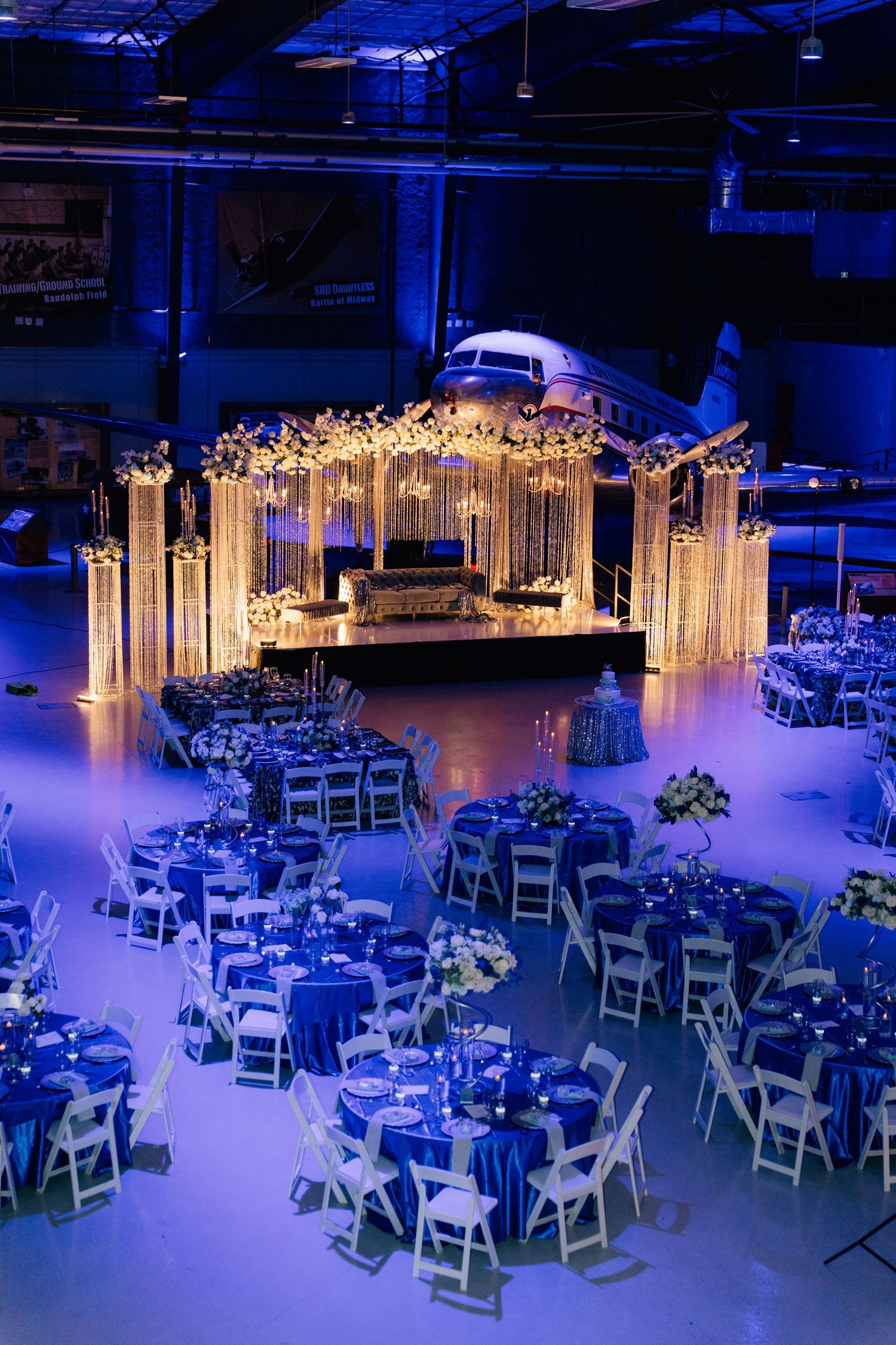 Wedding reception venue decorated with white chairs and blue lighting effects.