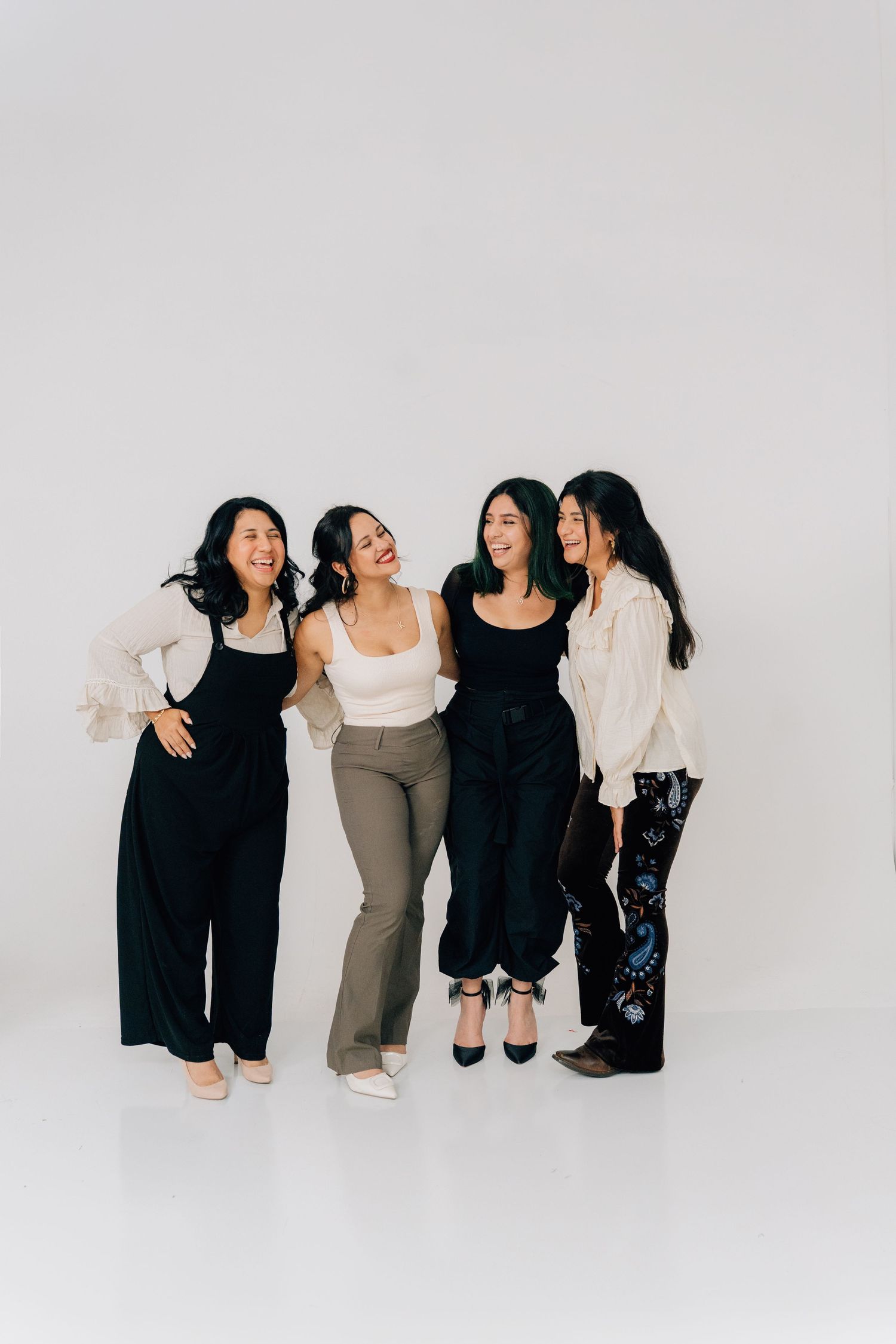 Creative team poses together in coordinated black and neutral outfits.