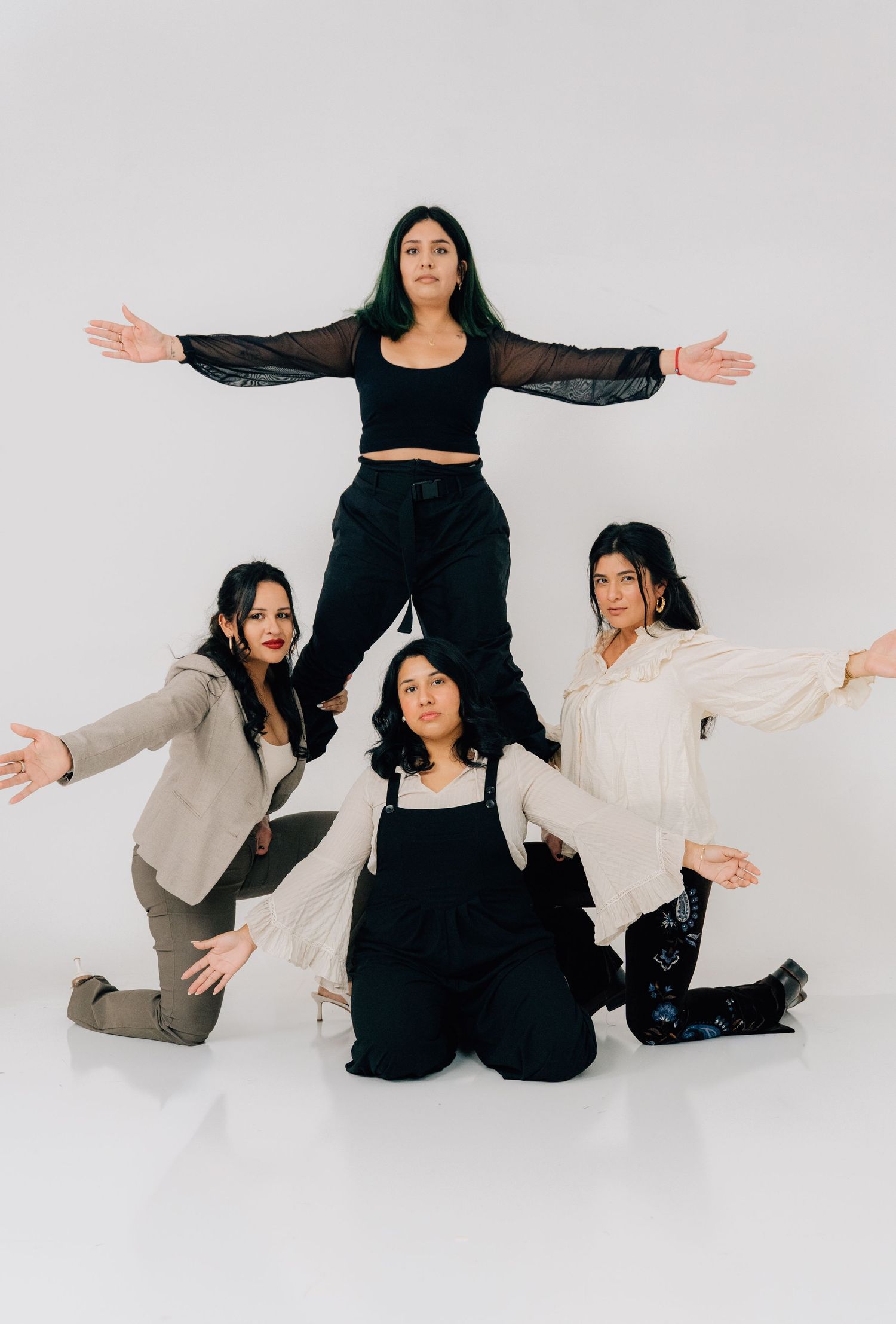 Group creates dynamic pose formation with arms outstretched against white backdrop.