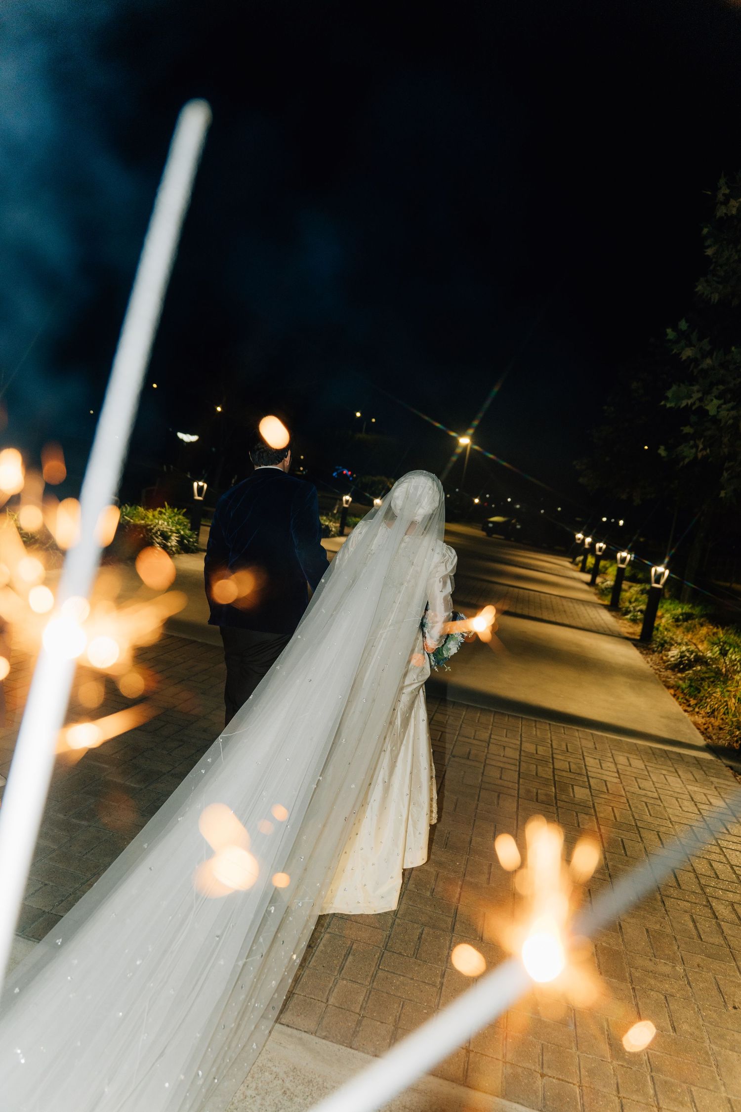 Sparklers illuminate a romantic nighttime wedding scene on a brick patio.