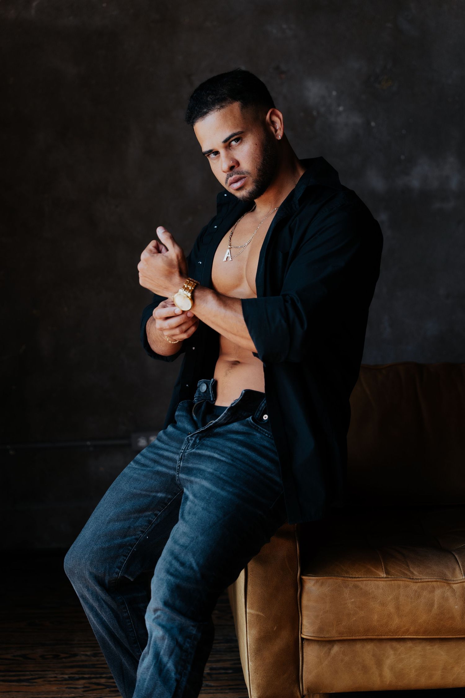 Moody portrait on leather couch with dramatic lighting and shadows.